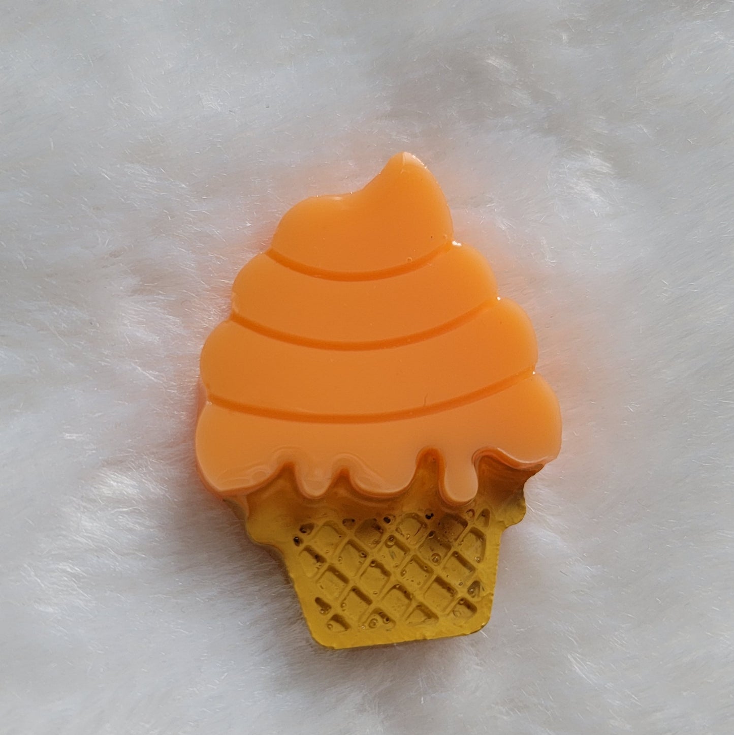 Ice cream cone shaped epoxy resin piece, bright orange color mimics creamsicle flavor ice cream and cone details painted in acrylic paint.