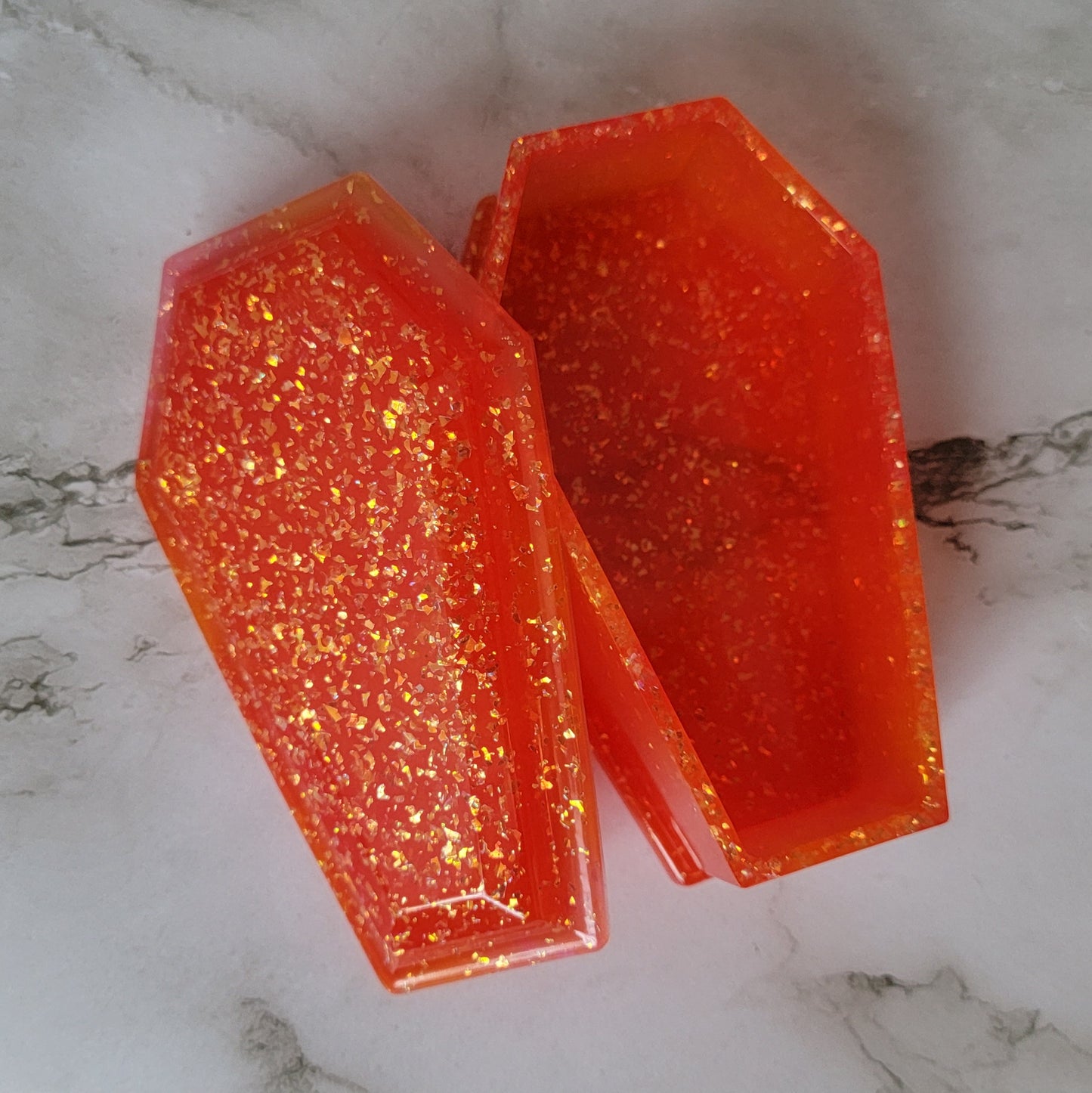Coffin shaped epoxy resin trinket box, neon orange with irregular iridescent glitter.