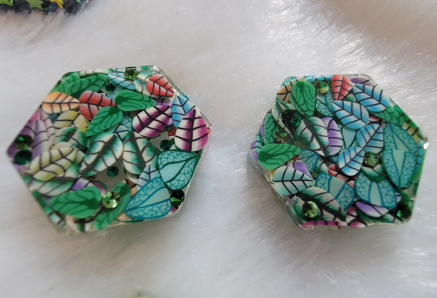 Two mini hexagon epoxy resin pieces, made with mixed polymer clay leaves and green rhinestones.