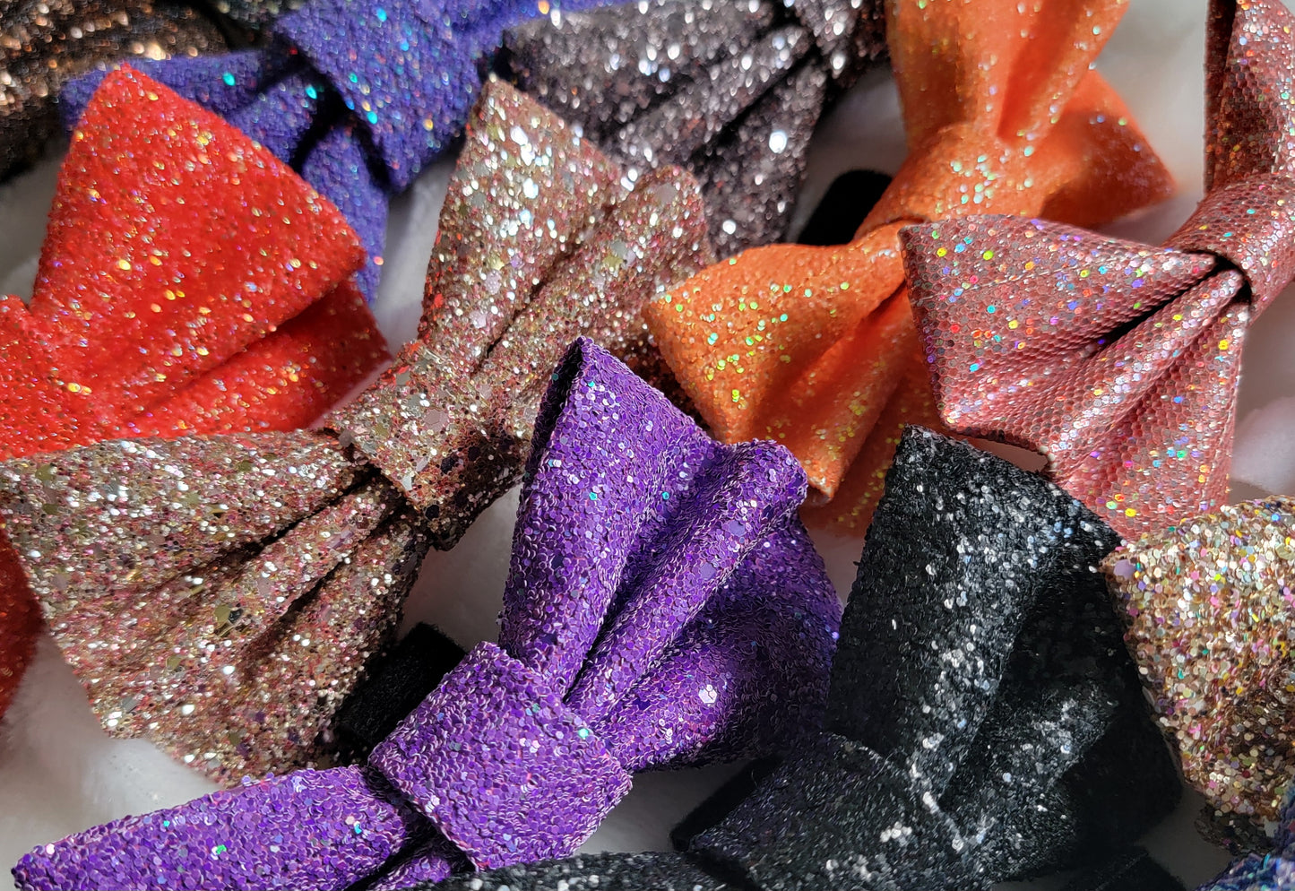 Array of several glitter bows in various fall colors including orange, purple, gold, black and red.
