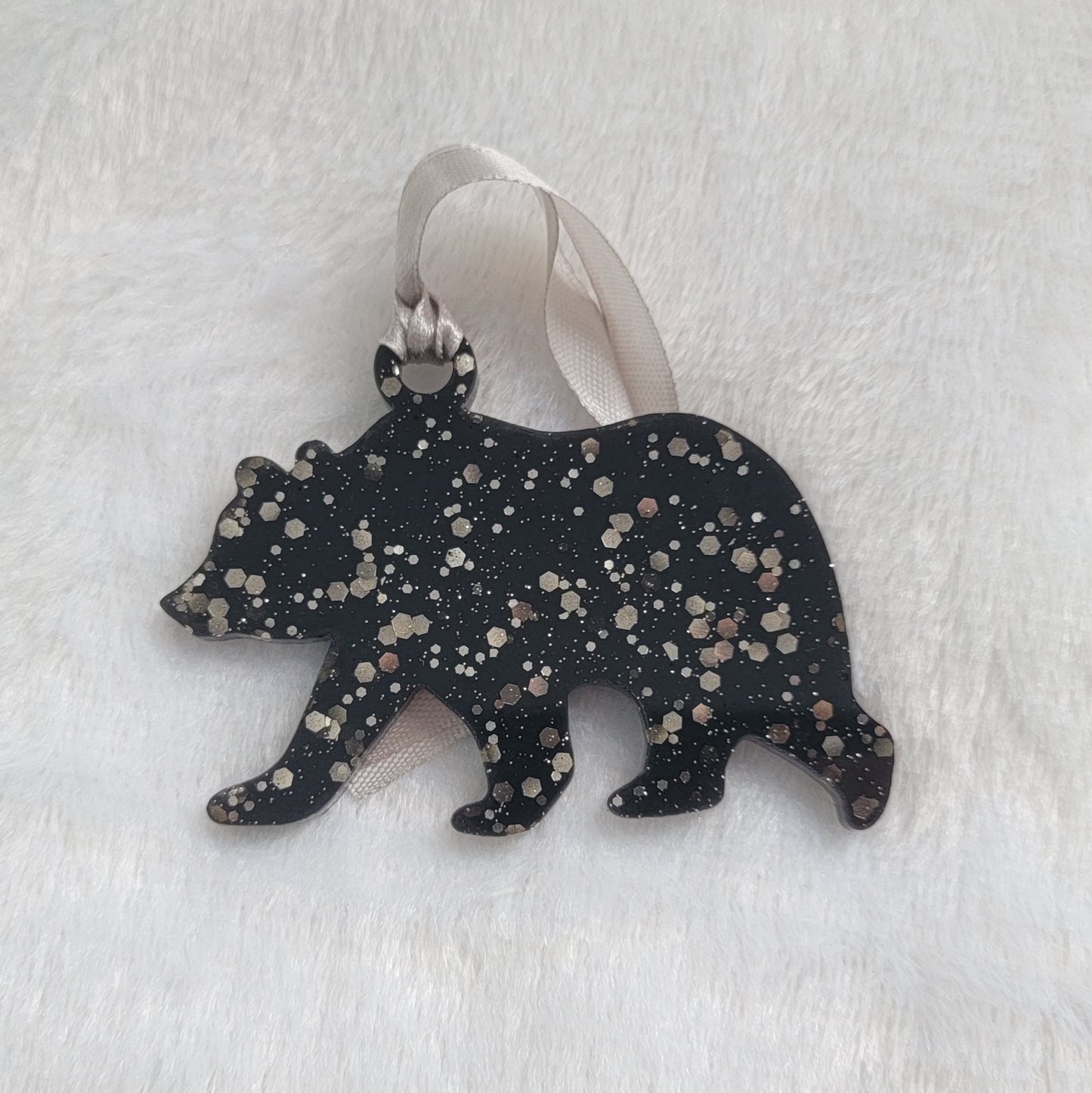 Bear shaped epoxy resin ornament, made with black pigment and warm silver glitter combined and a silver ribbon attached.