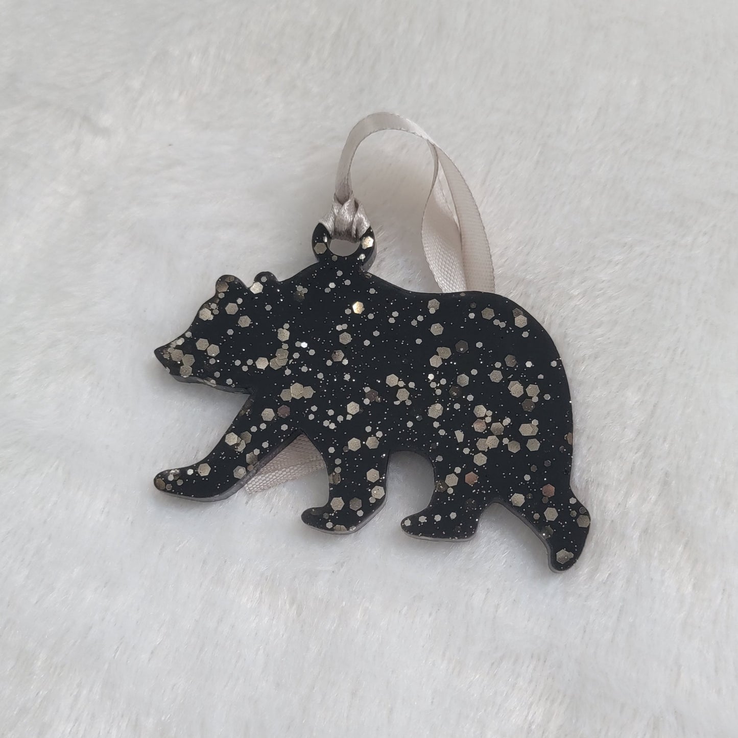 Bear shaped epoxy resin ornament, made with black pigment and warm silver glitter combined and a silver ribbon attached.