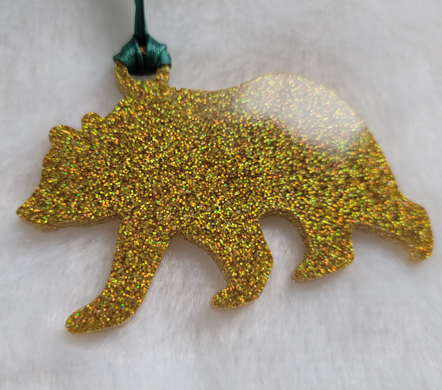 Bear shaped epoxy resin ornament, made with gold holographic glitter and a dark green ribbon attached.