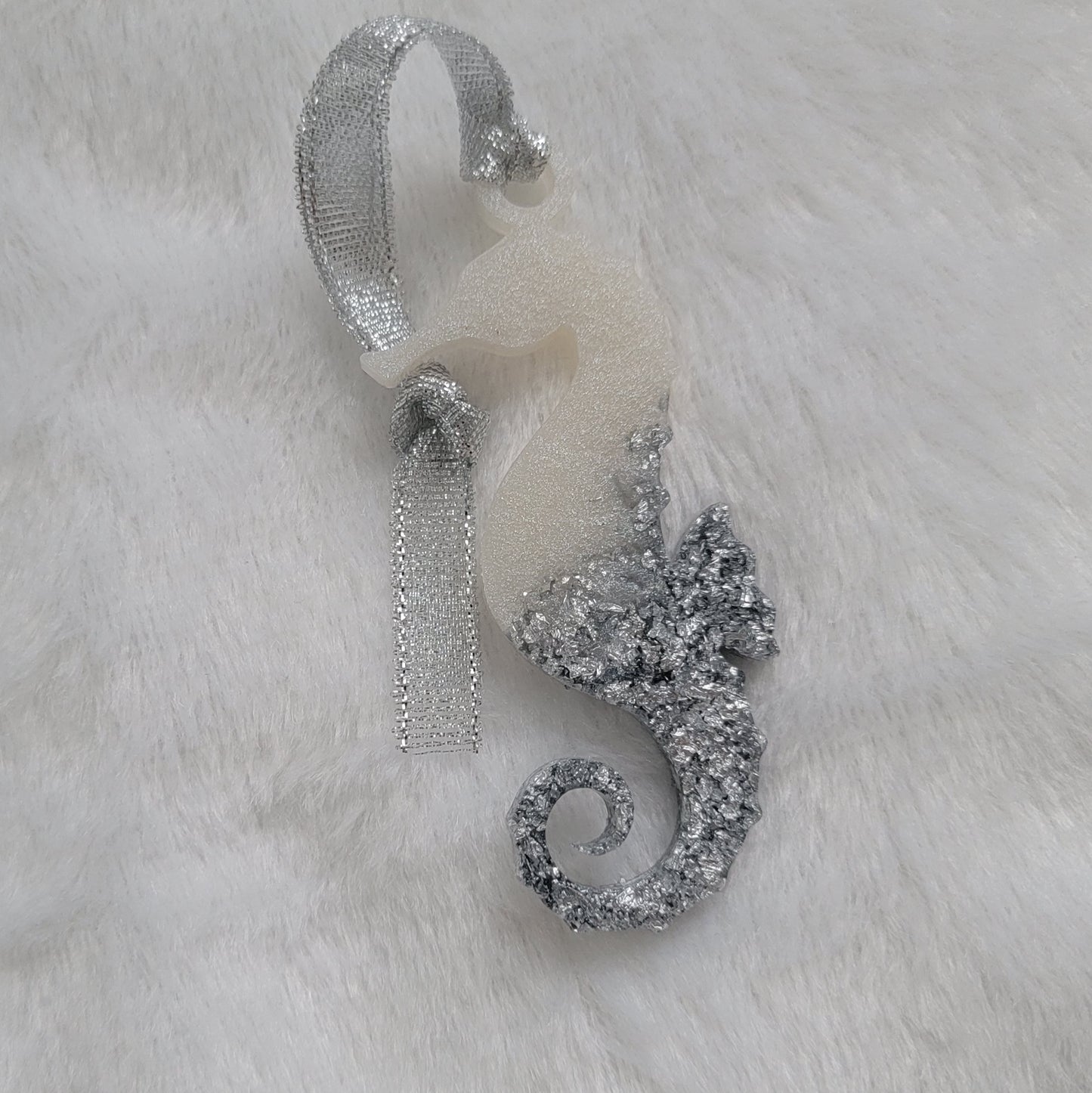 Seahorse shaped epoxy resin ornament, made with white pigment and silver foil flakes and a sparkling silver ribbon attached.