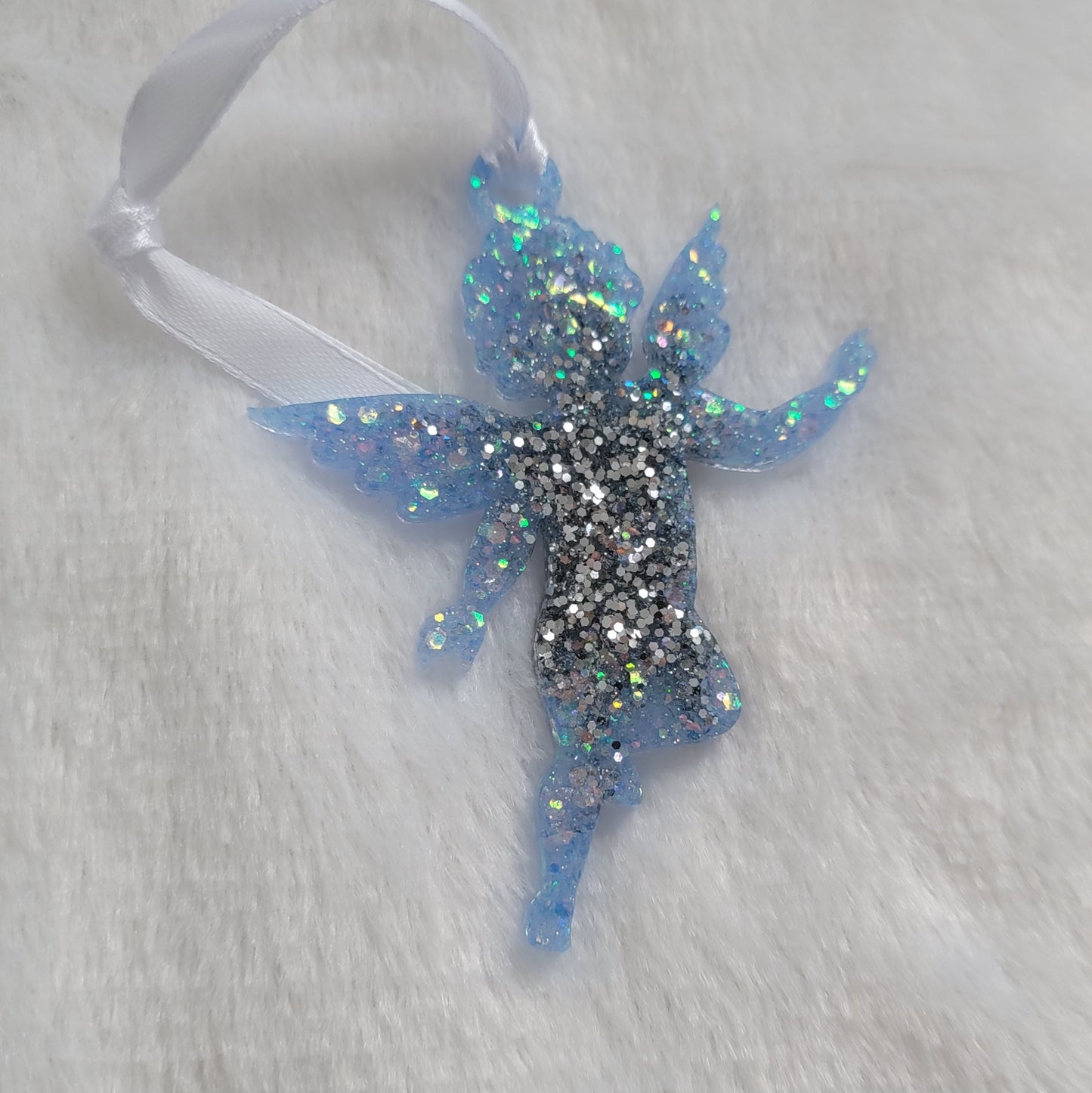 Cherub shaped epoxy resin ornament, made with bright silver and light blue iridescent glitter and a white ribbon attached.