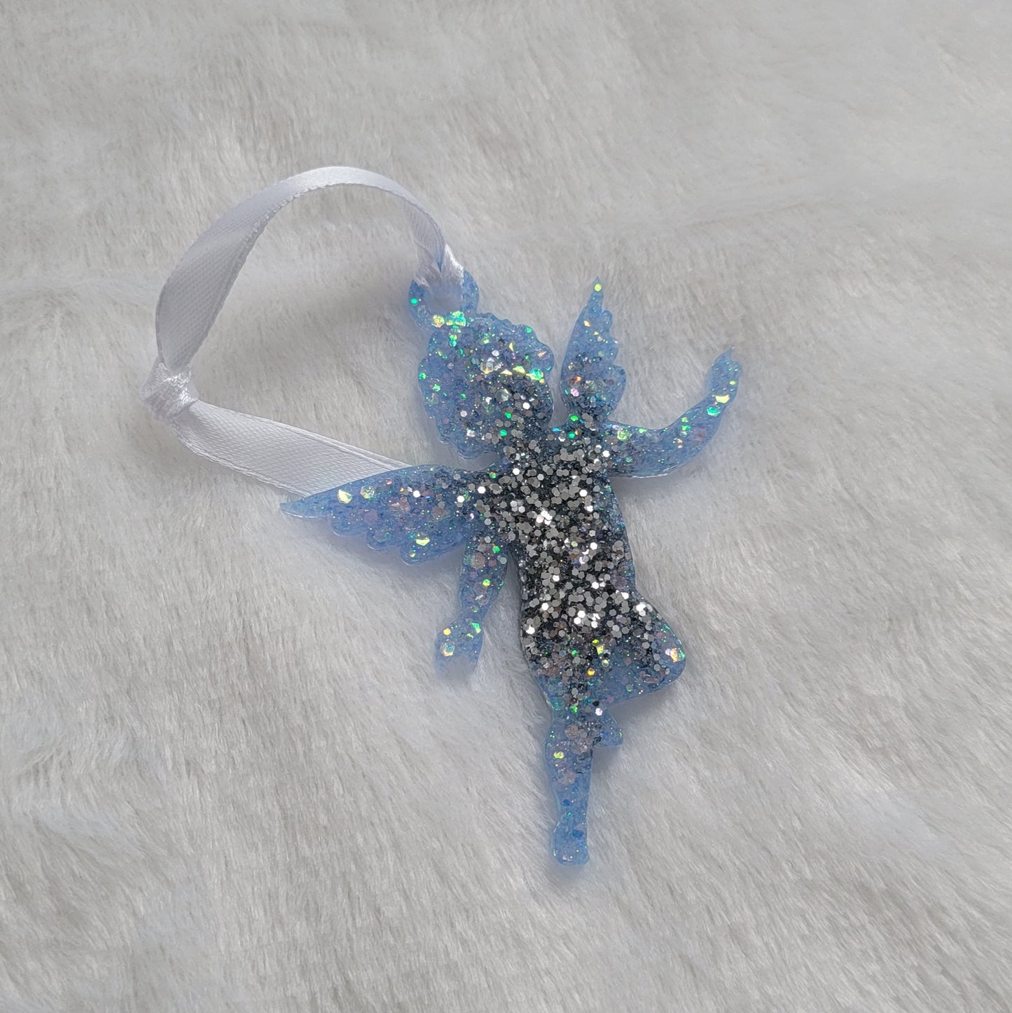 Cherub shaped epoxy resin ornament, made with bright silver and light blue iridescent glitter and a white ribbon attached.