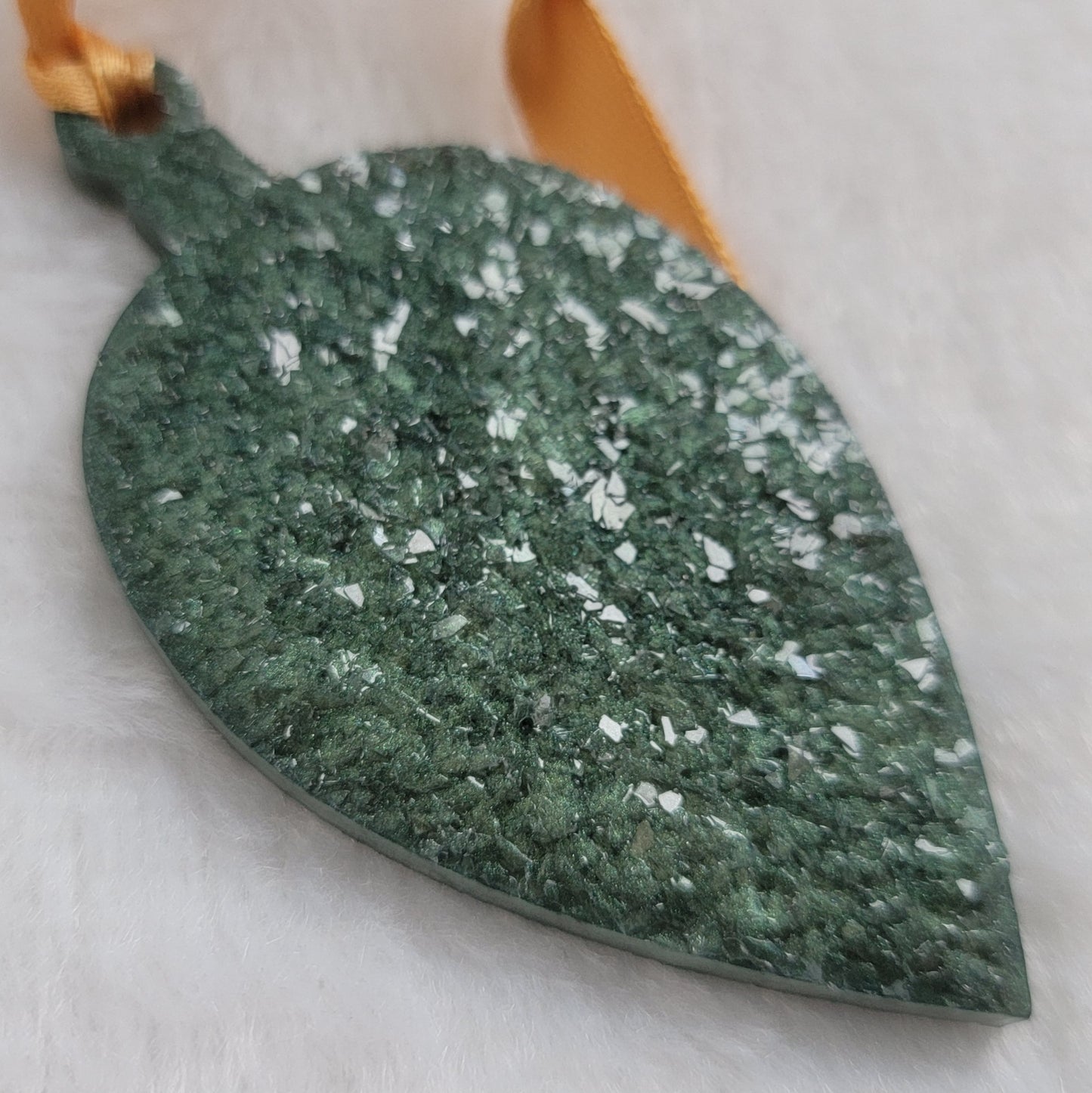 Drop shaped epoxy resin ornament that has a crystalline texture, made with green pigment and a gold ribbon attached.