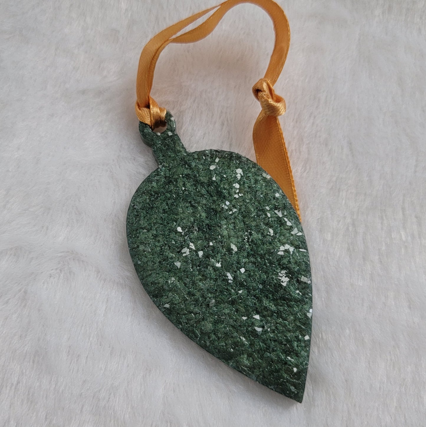 Drop shaped epoxy resin ornament that has a crystalline texture, made with green pigment and a gold ribbon attached.