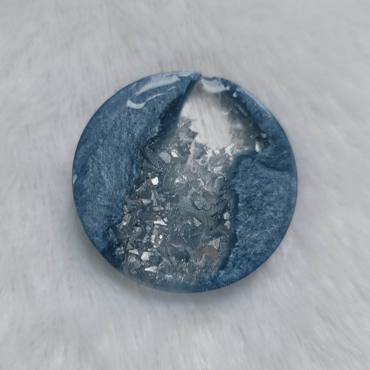 Round epoxy resin piece made with ice blue mica pigment and silver crystalline texture inset running through the center of the piece.