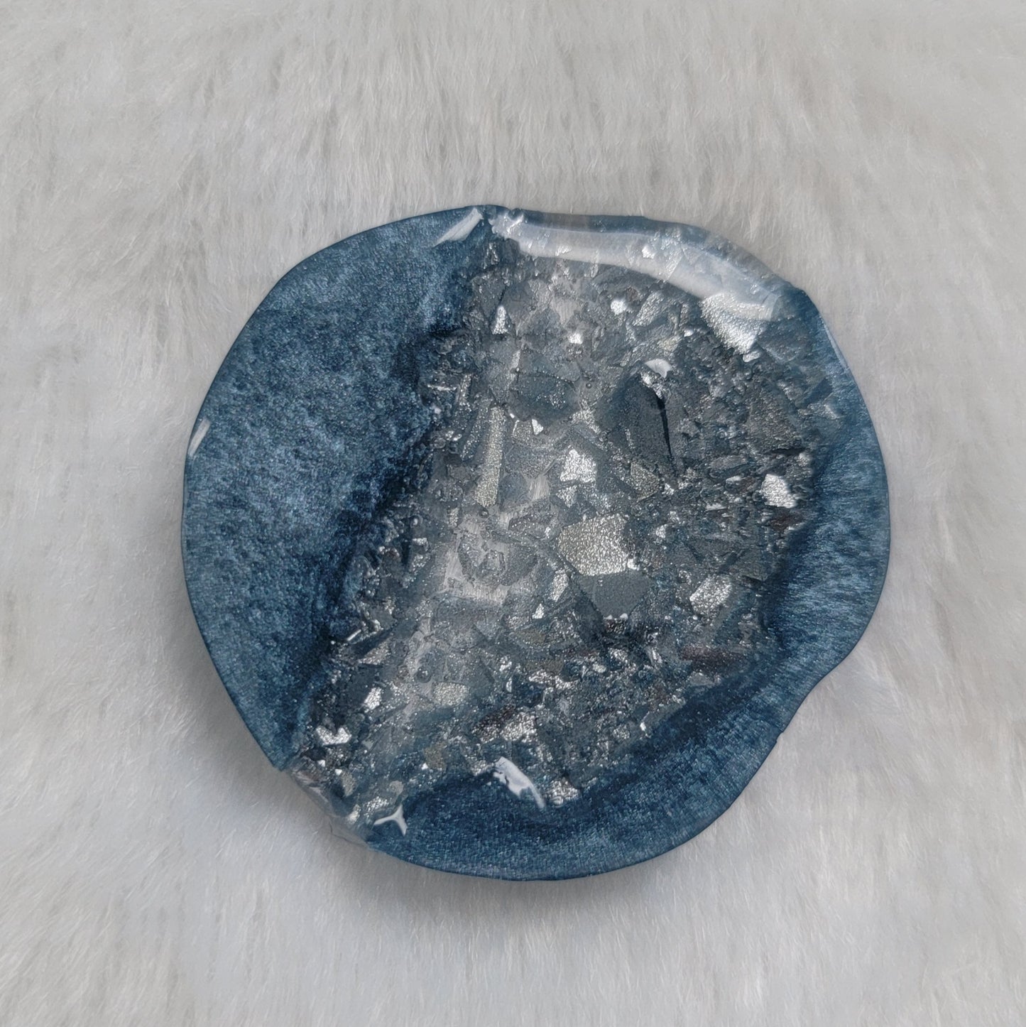 Irregular round epoxy resin piece made with ice blue mica pigment and silver crystalline texture inset running through the center of the piece.