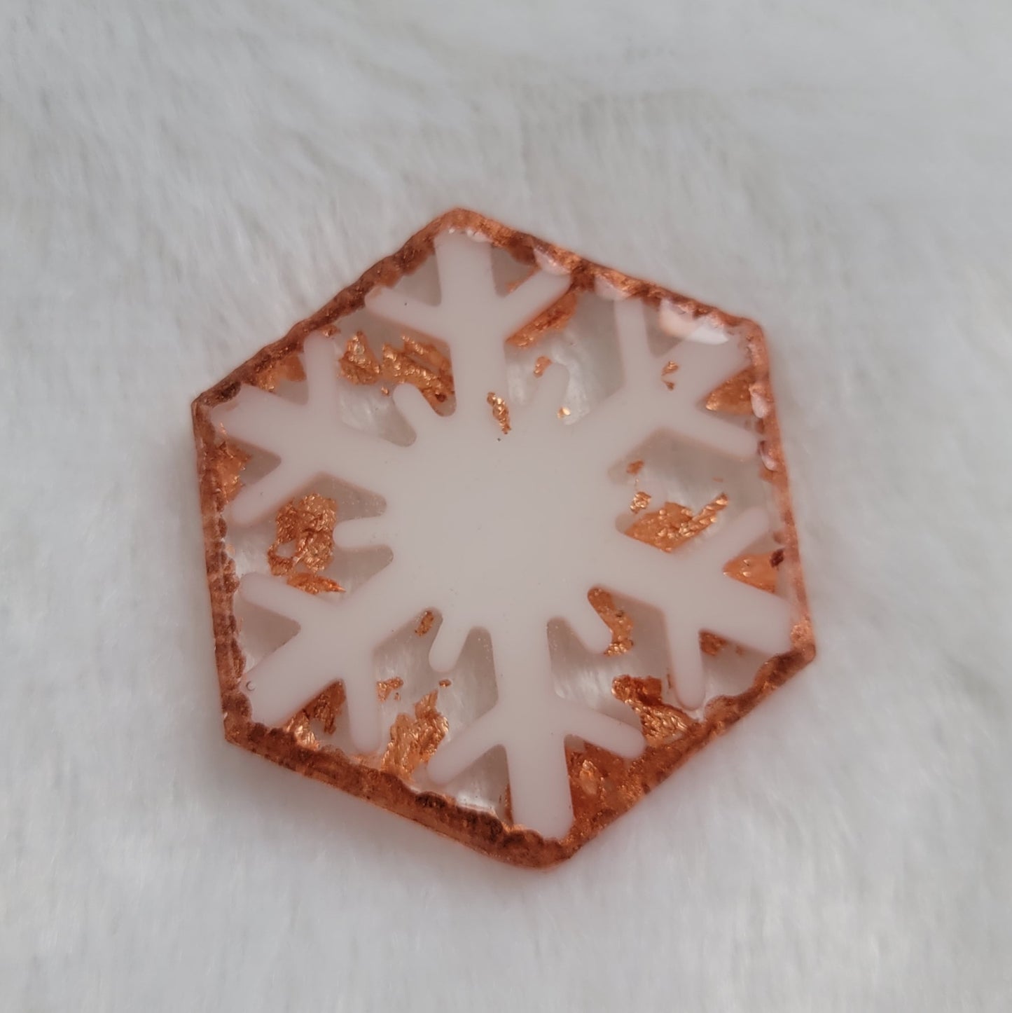 Hexagon shaped epoxy resin piece that contains a white resin snowflake, copper foil flakes, and has metallic copper edges that imitate hammered metal.