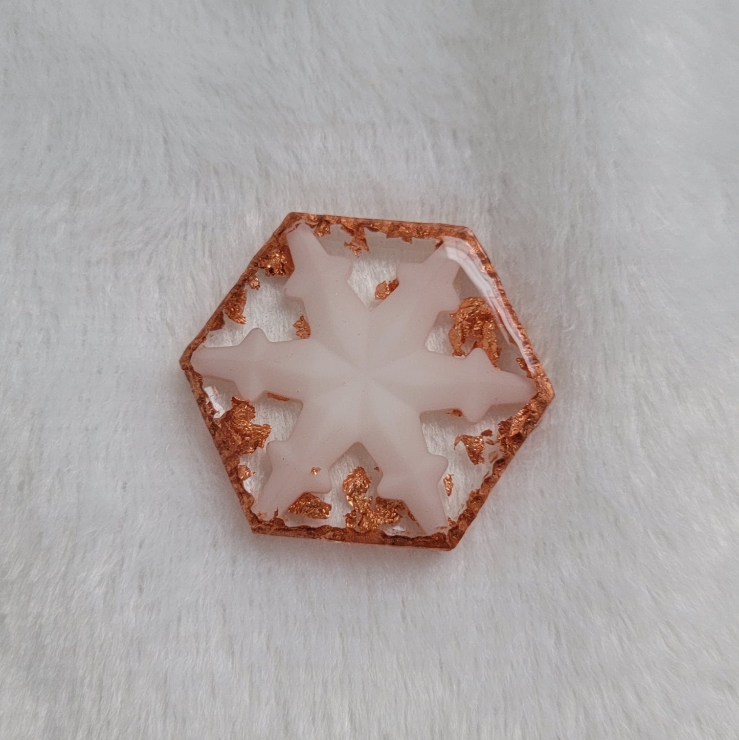 Hexagon shaped epoxy resin piece that contains a white resin snowflake, copper foil flakes, and has metallic copper edges that imitate hammered metal.