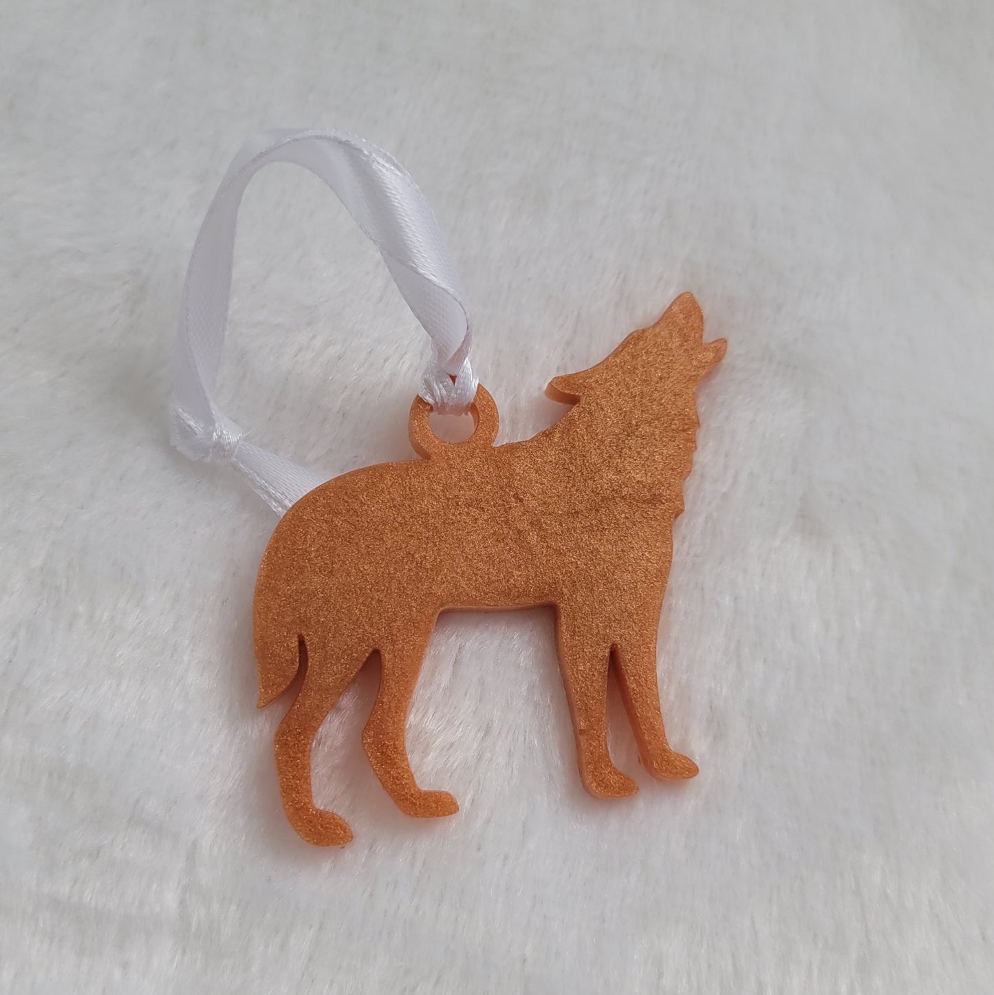 Wolf shaped epoxy resin ornament, made with golden bronze pigment and a white ribbon attached.