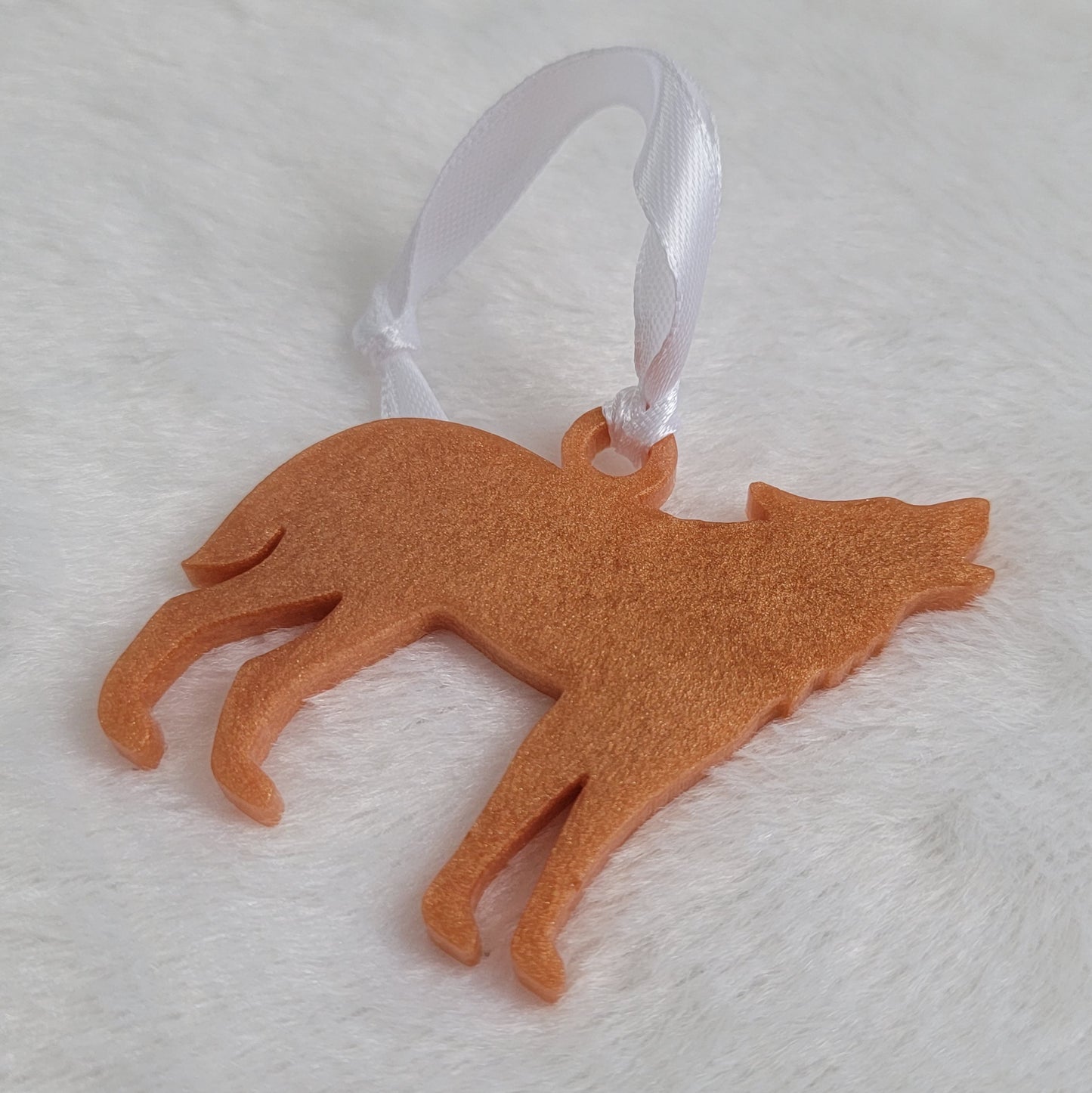 Wolf shaped epoxy resin ornament, made with golden bronze pigment and a white ribbon attached.