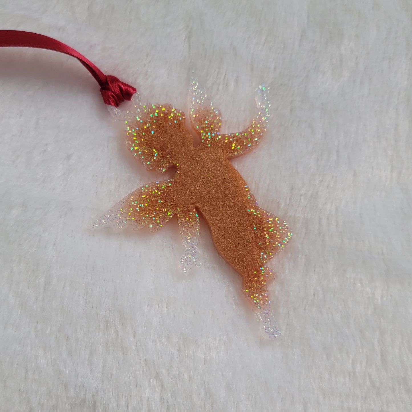 Cherub shaped epoxy resin ornament, made with golden bronze pigment and white iridescent glitter and a red ribbon attached.