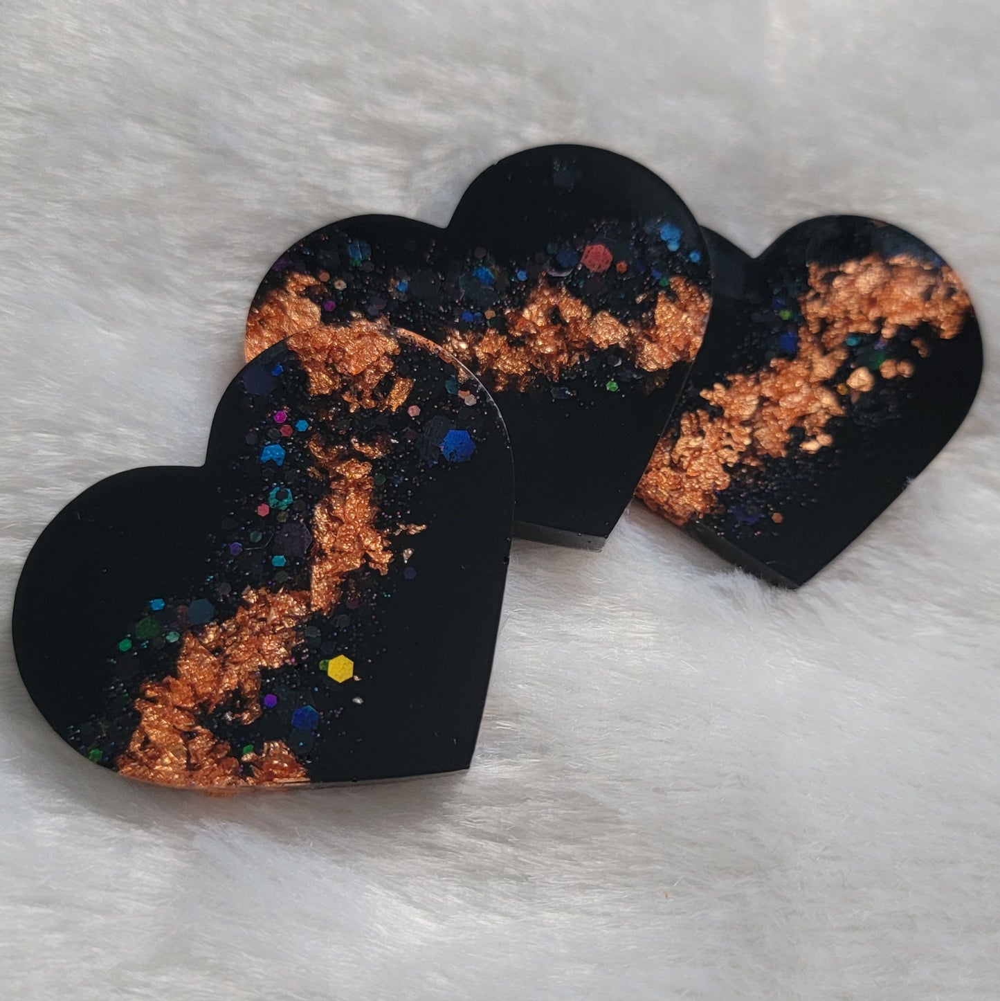Three resin heart shaped pieces made with black pigment, black holographic glitter and copper foil flakes.