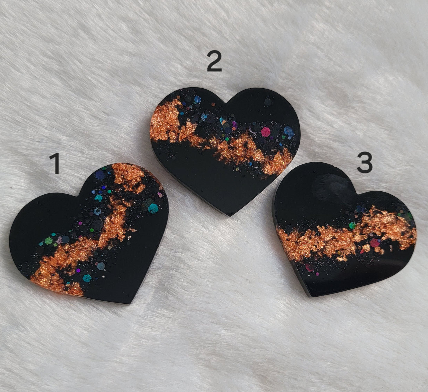 Three resin heart shaped pieces made with black pigment, black holographic glitter and copper foil flakes.