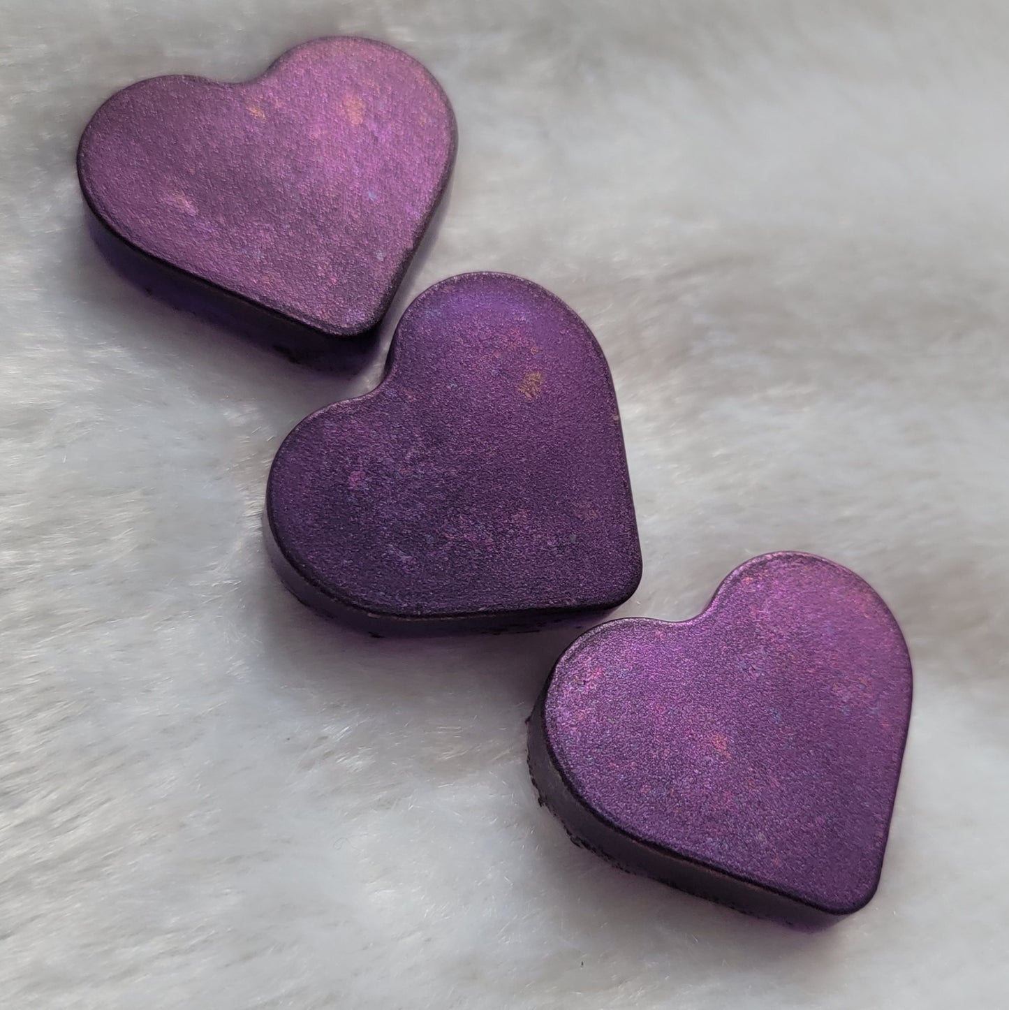 Three mini heart shaped resin pieces made with translucent purple pigment and iridescent color shift coating.