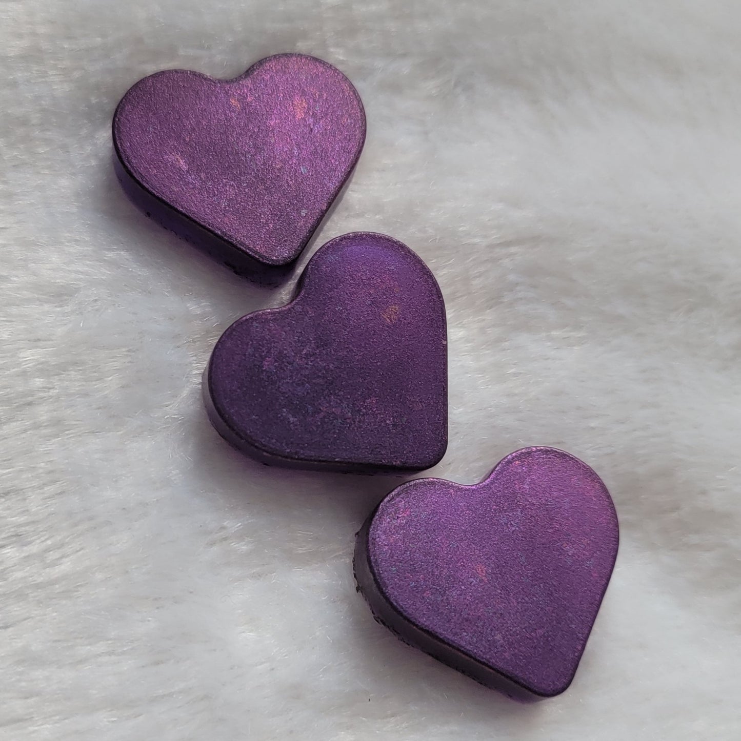 Three mini heart shaped resin pieces made with translucent purple pigment and iridescent color shift coating.