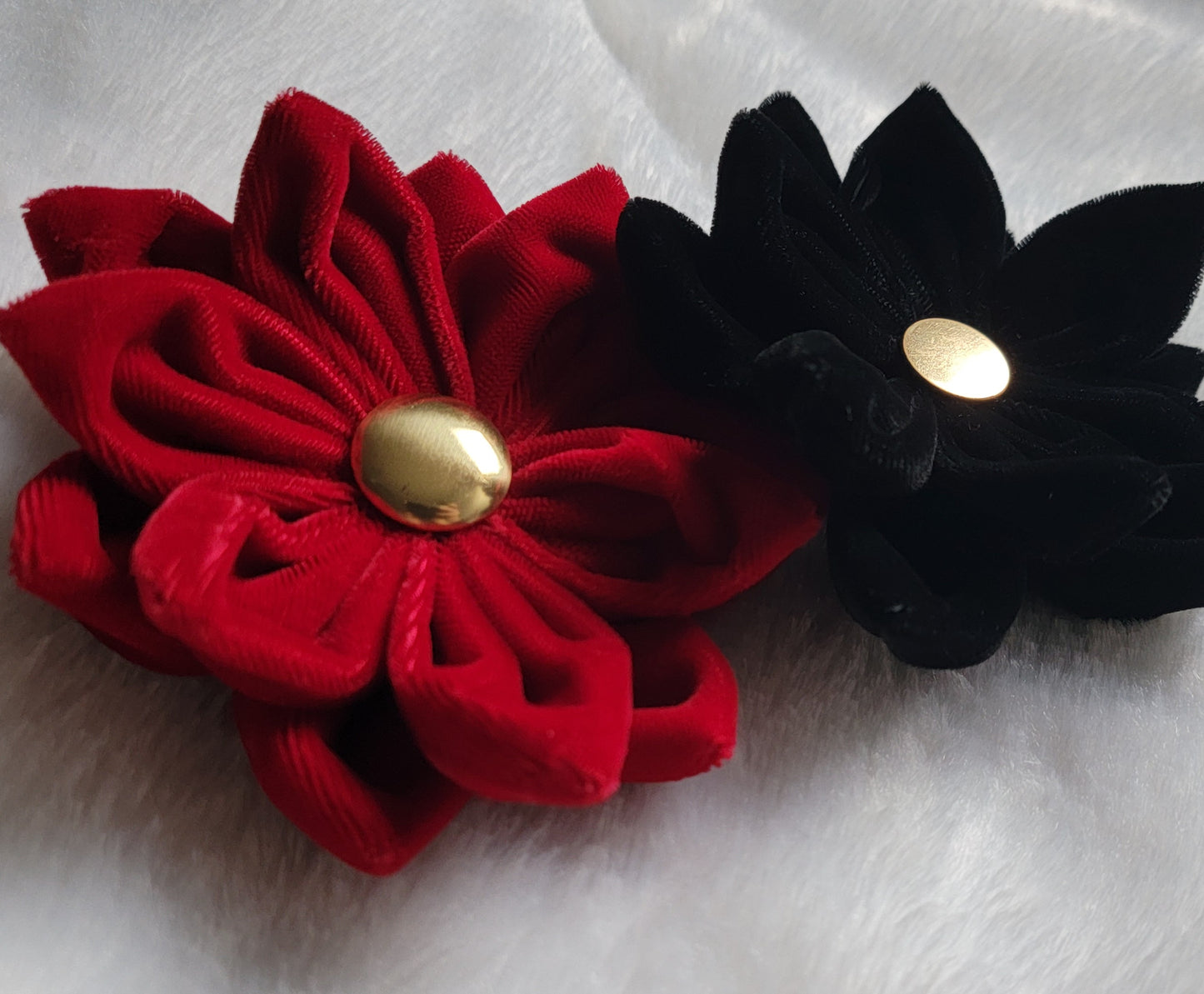 Two velvet flower accessories, red and black, with golden button centers.