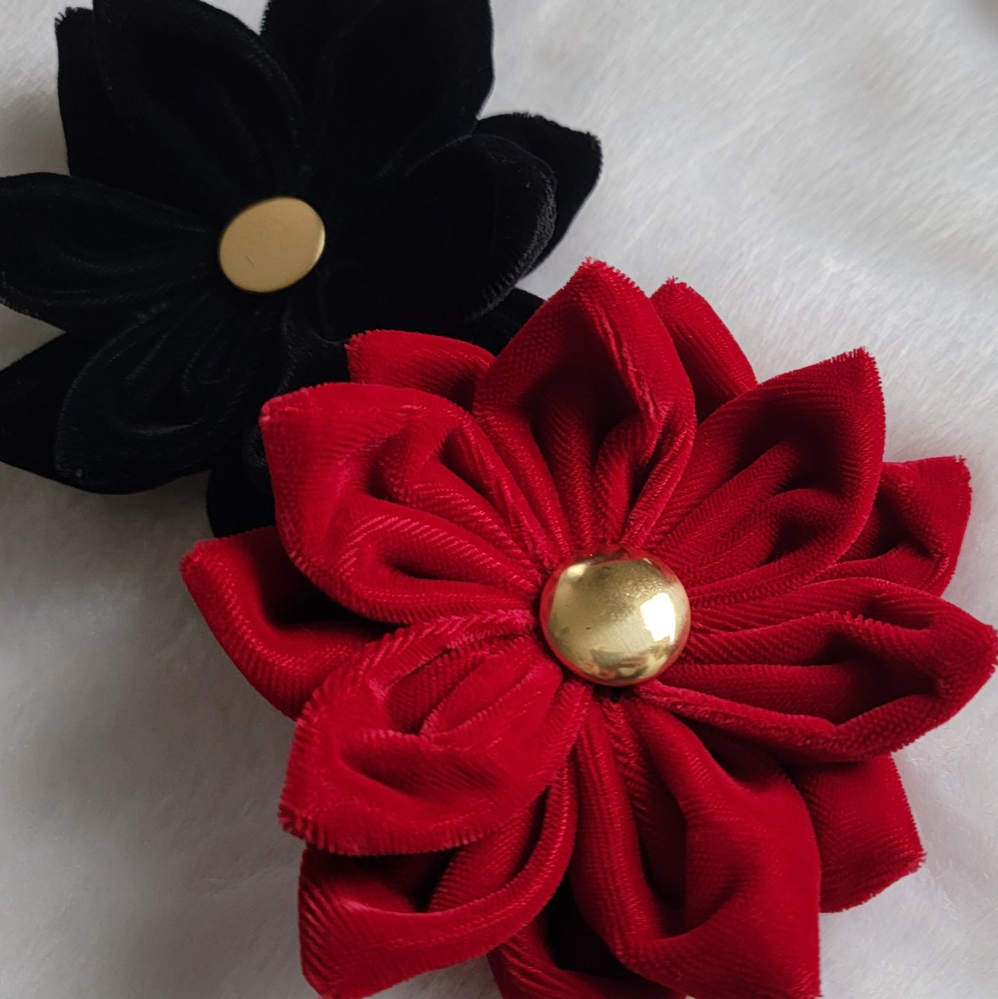 Two velvet flower accessories, red and black, with golden button centers.