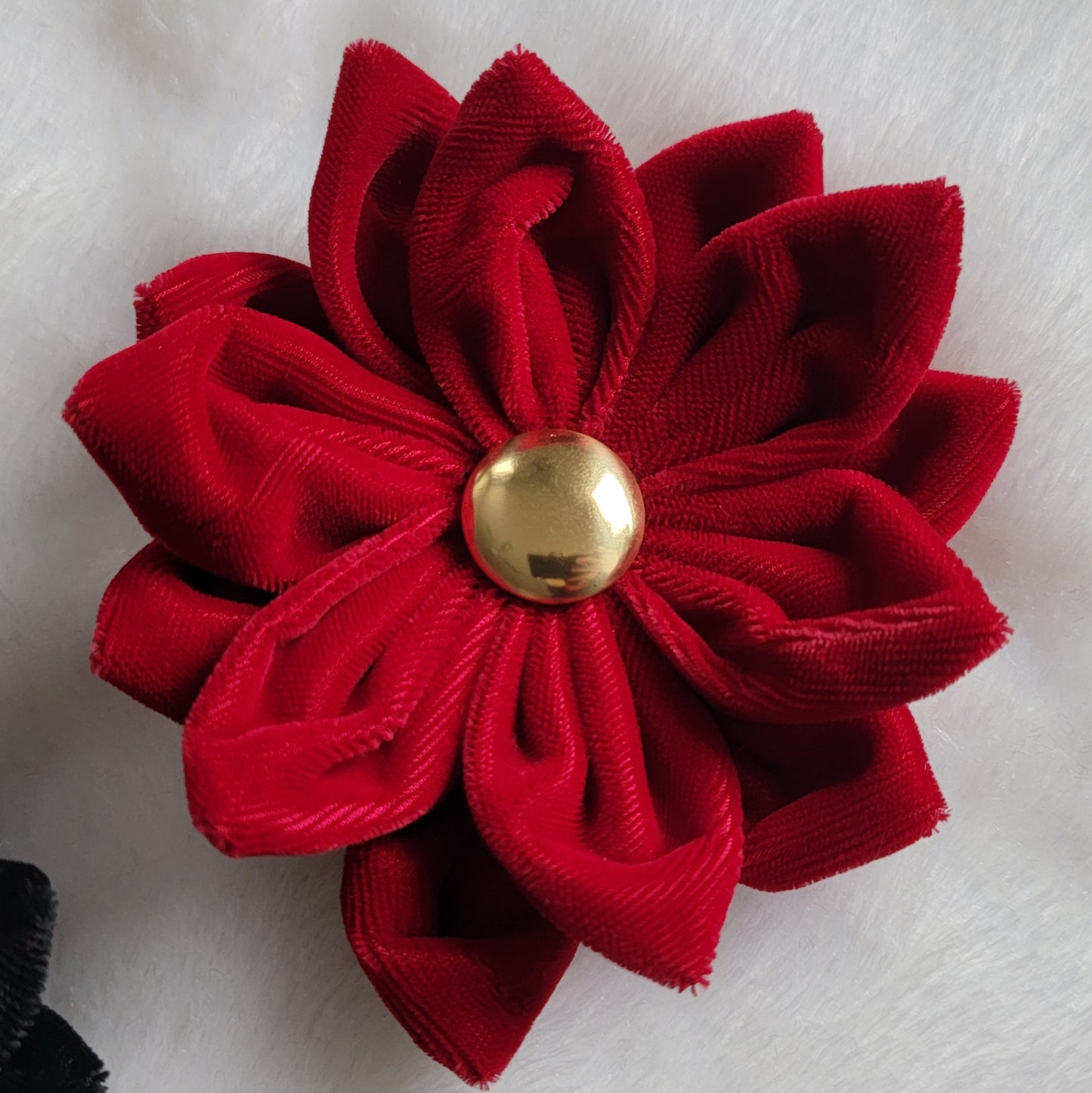 Red velvet flower accessory with golden button center.