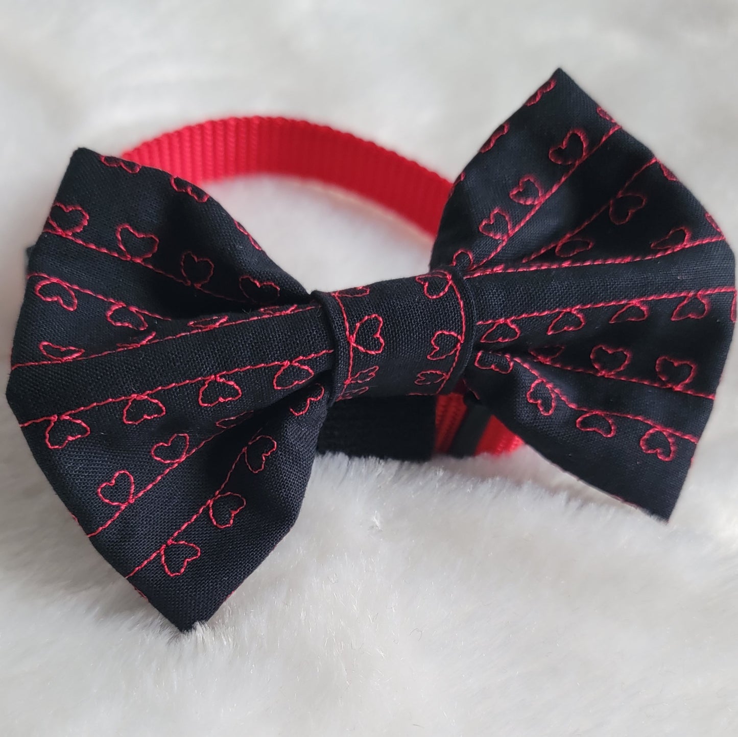 Small fabric bowtie accessory made with black cotton and red stitched hearts.