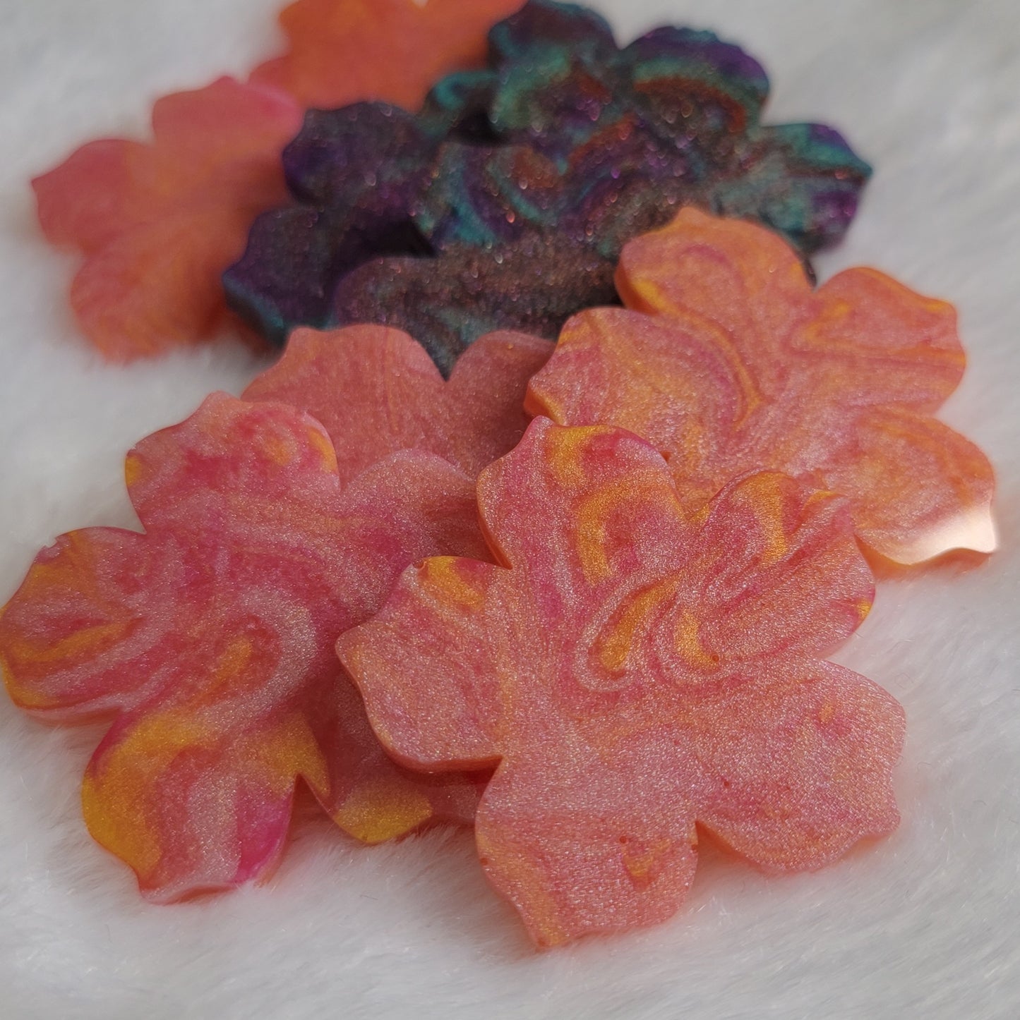 Array of flower blossom shaped epoxy resin pieces with swirled pigments.