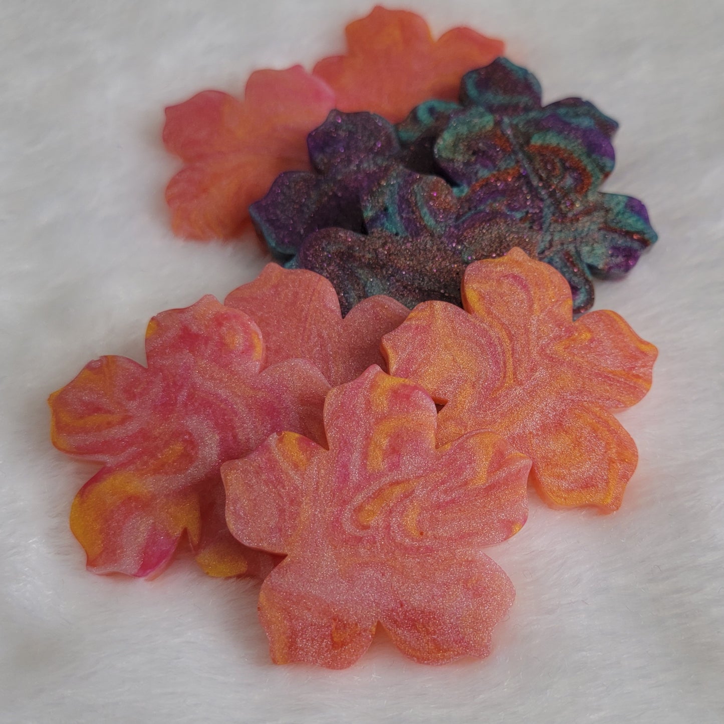 Array of flower blossom shaped epoxy resin pieces with swirled pigments.
