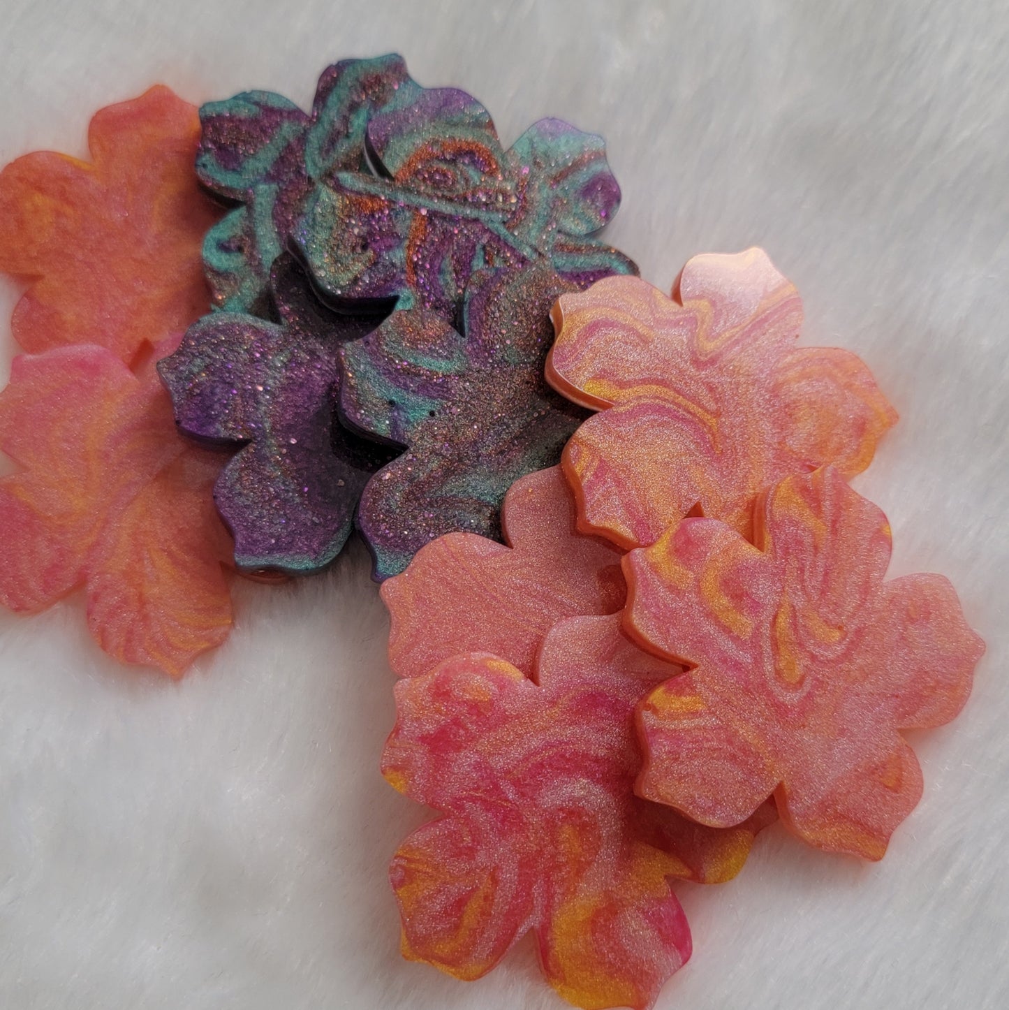 Array of flower blossom shaped epoxy resin pieces with swirled pigments.