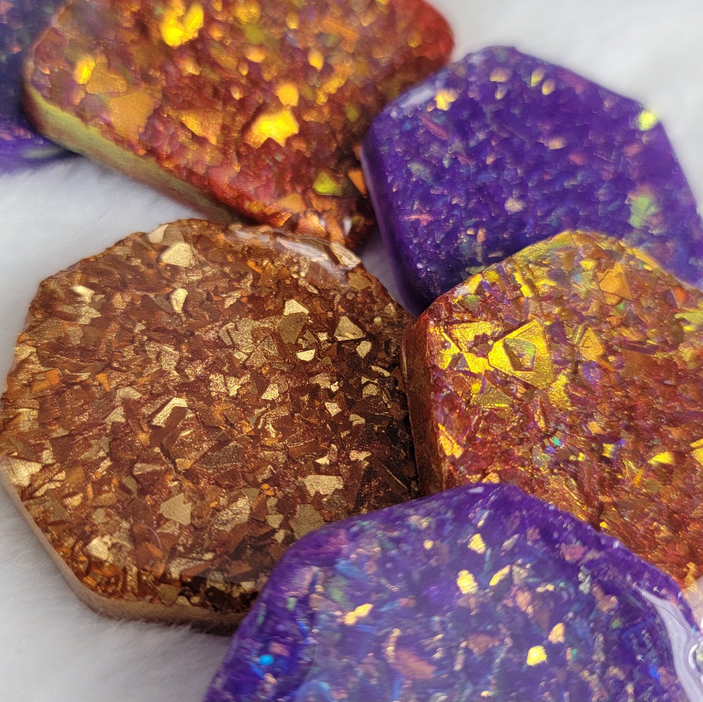 Epoxy resin pieces with shimmering golden iridescent crystalline texture encased within and red and purple pigment.