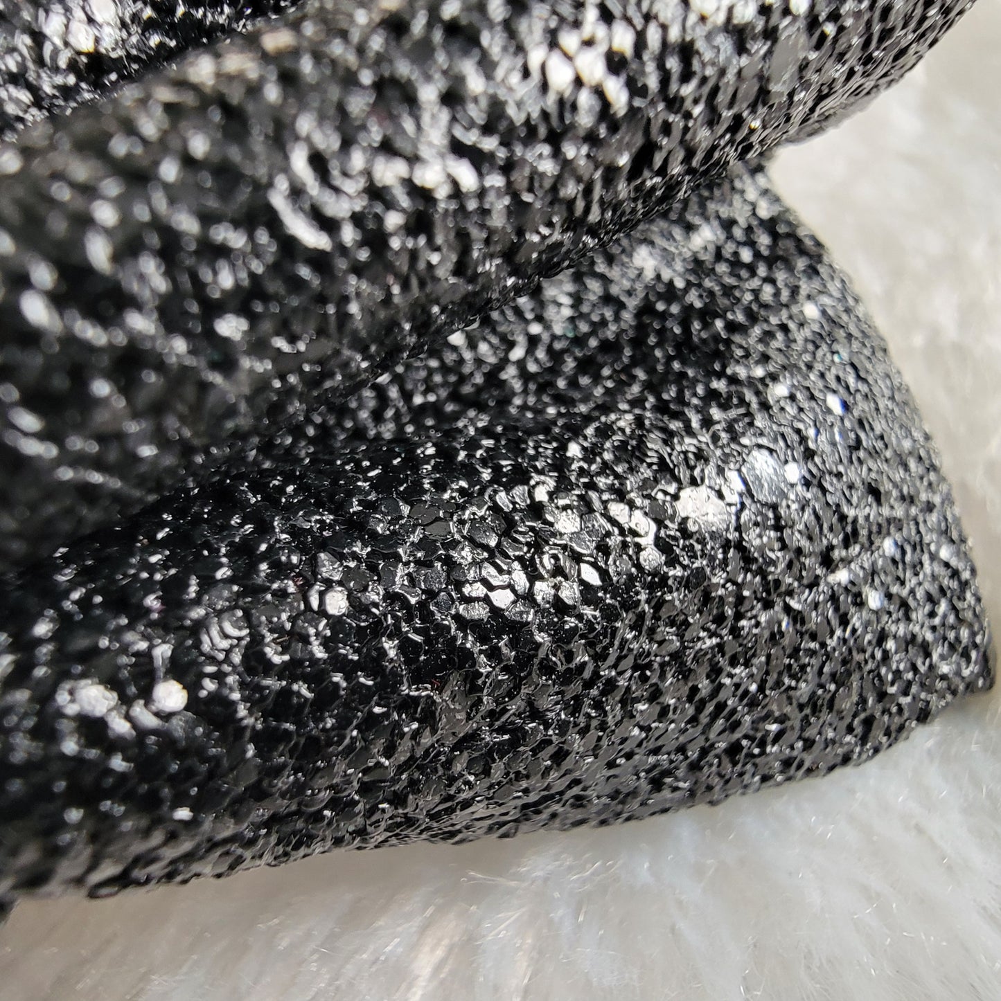 Close up view of black sparkle texture faux leather.