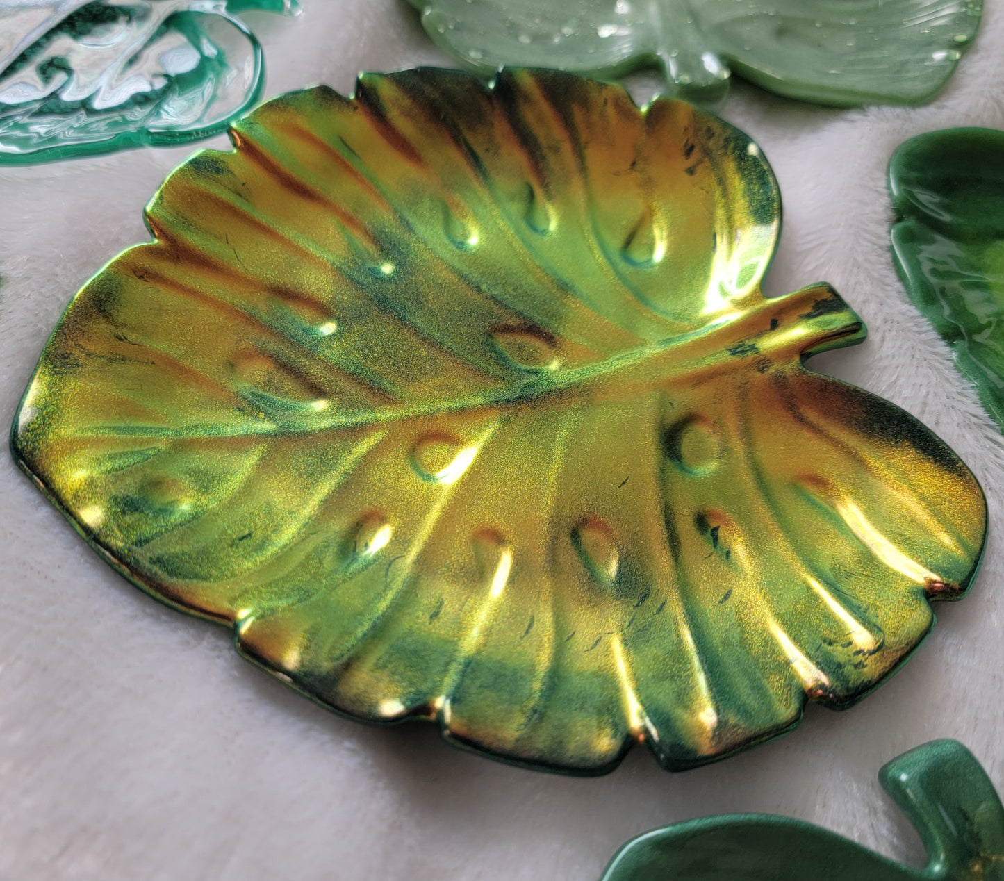 Monstera leaf shaped decorative dish made from epoxy resin, iridescent gold coating over dark green.