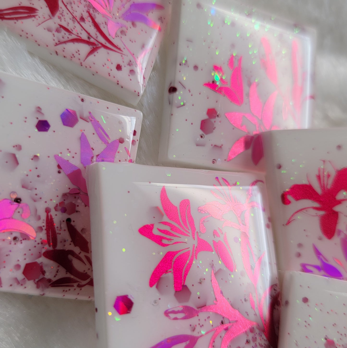 Six square epoxy resin pieces, bases are white with pink and opal glitter and each piece features a unique lily scene in metallic and holographic pink vinyl.