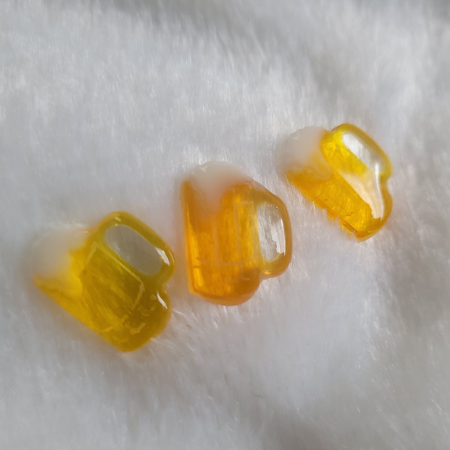 Three small beer mug shaped resin pieces in varied shades of amber.