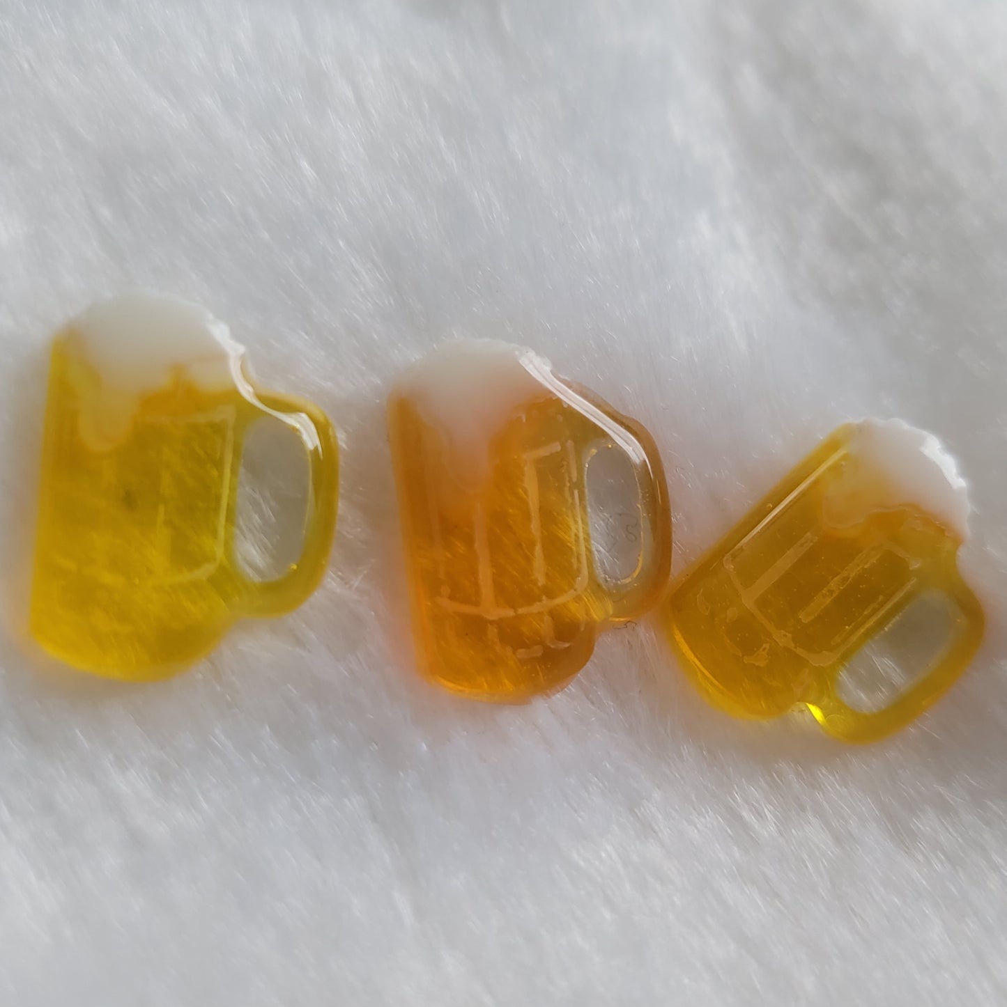 Three small beer mug shaped resin pieces in varied shades of amber.