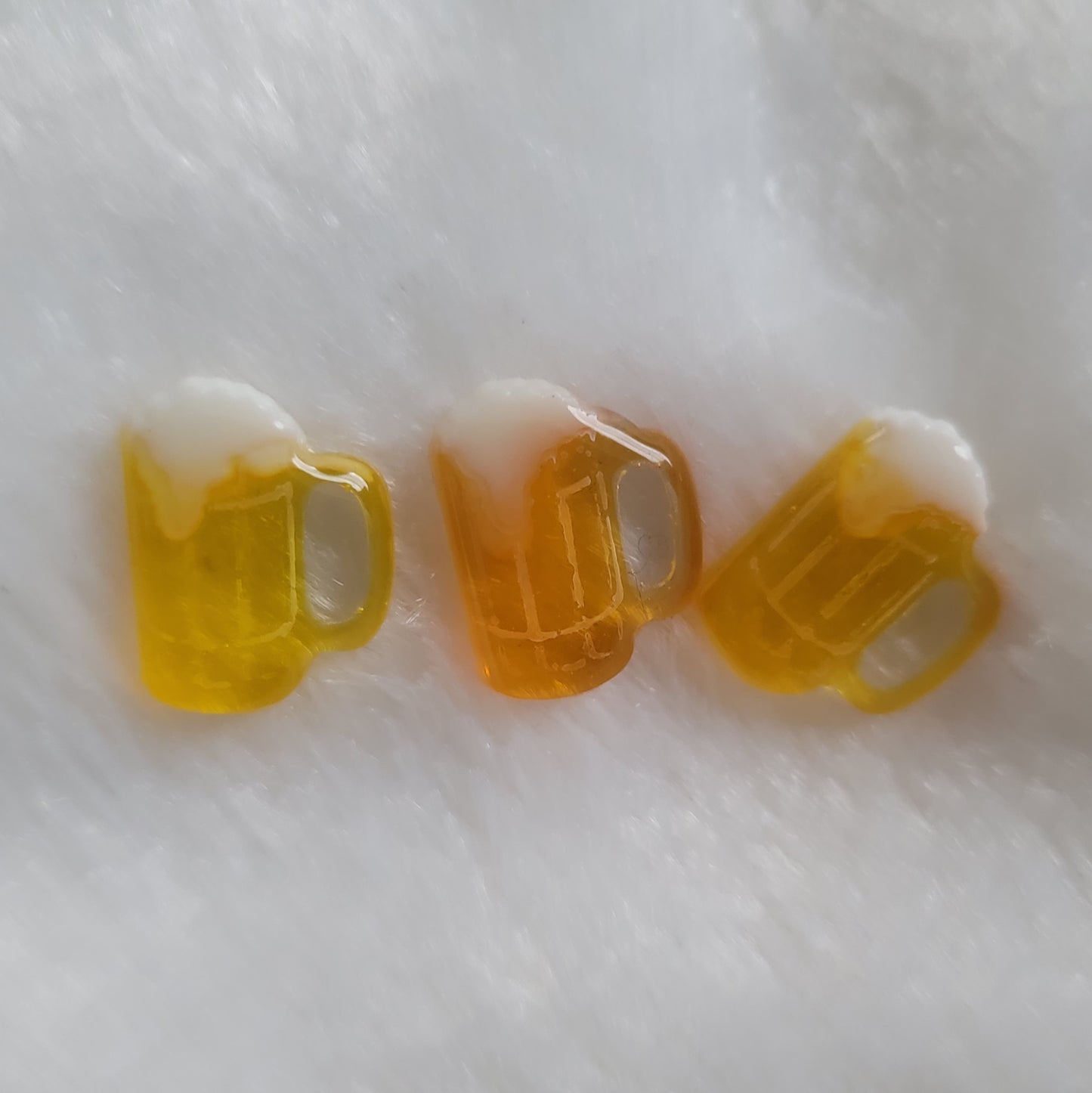 Three small beer mug shaped resin pieces in varied shades of amber.