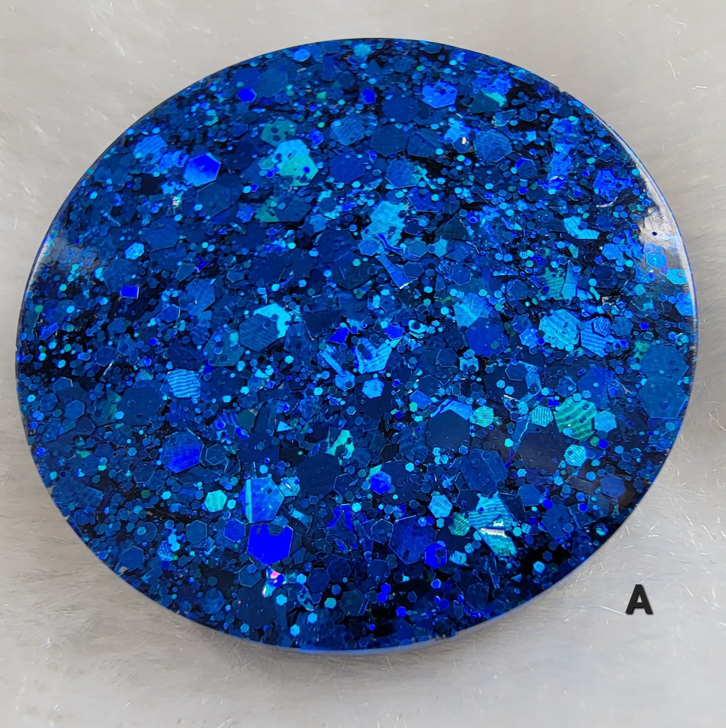 Close up of round epoxy resin piece made with deep blue glitter.