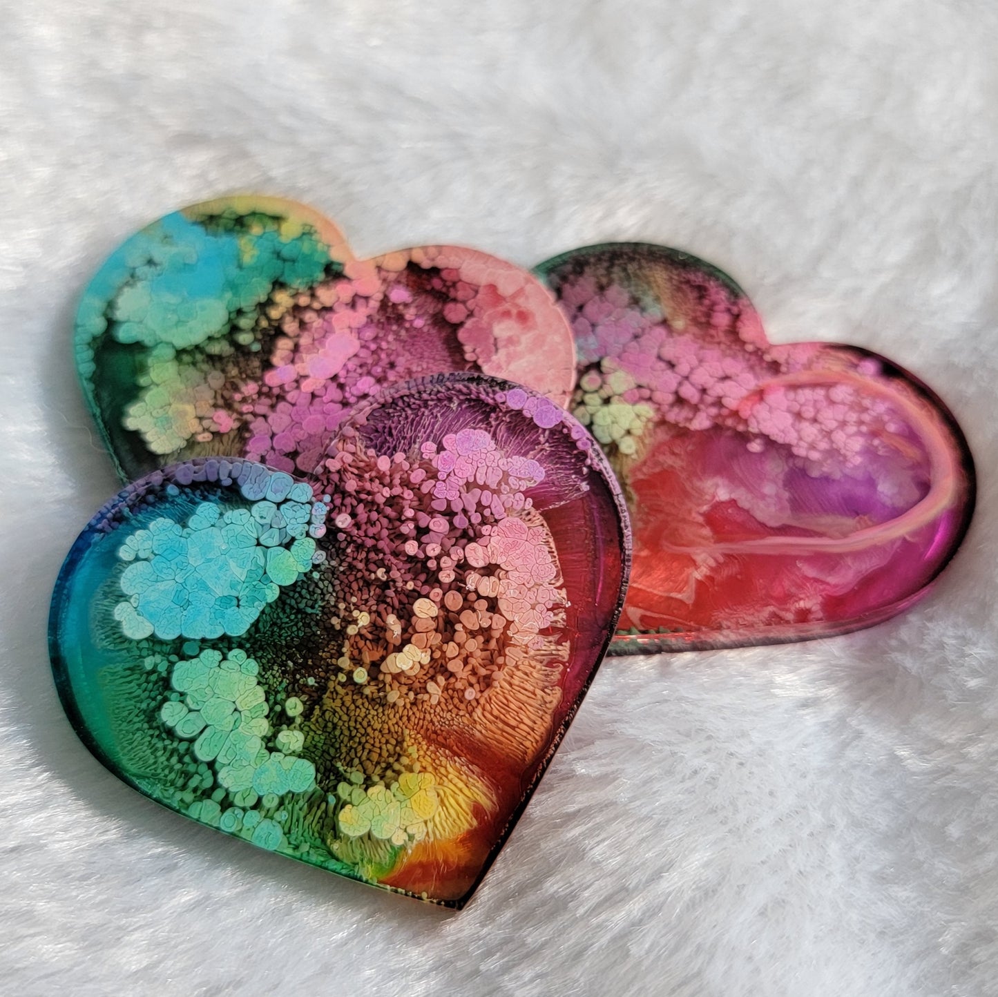 Three heart shaped epoxy resin pieces made with multicolored alcohol inks.