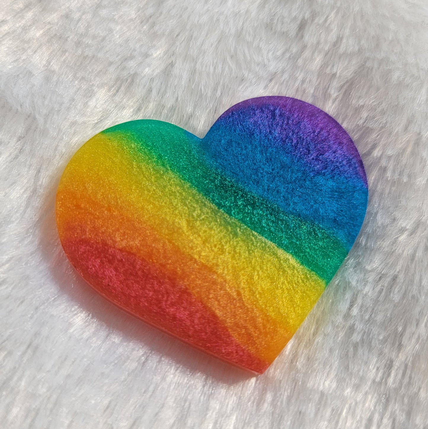 Heart shaped epoxy resin piece with diagonal rainbow stripes in shimmering mica pigments.