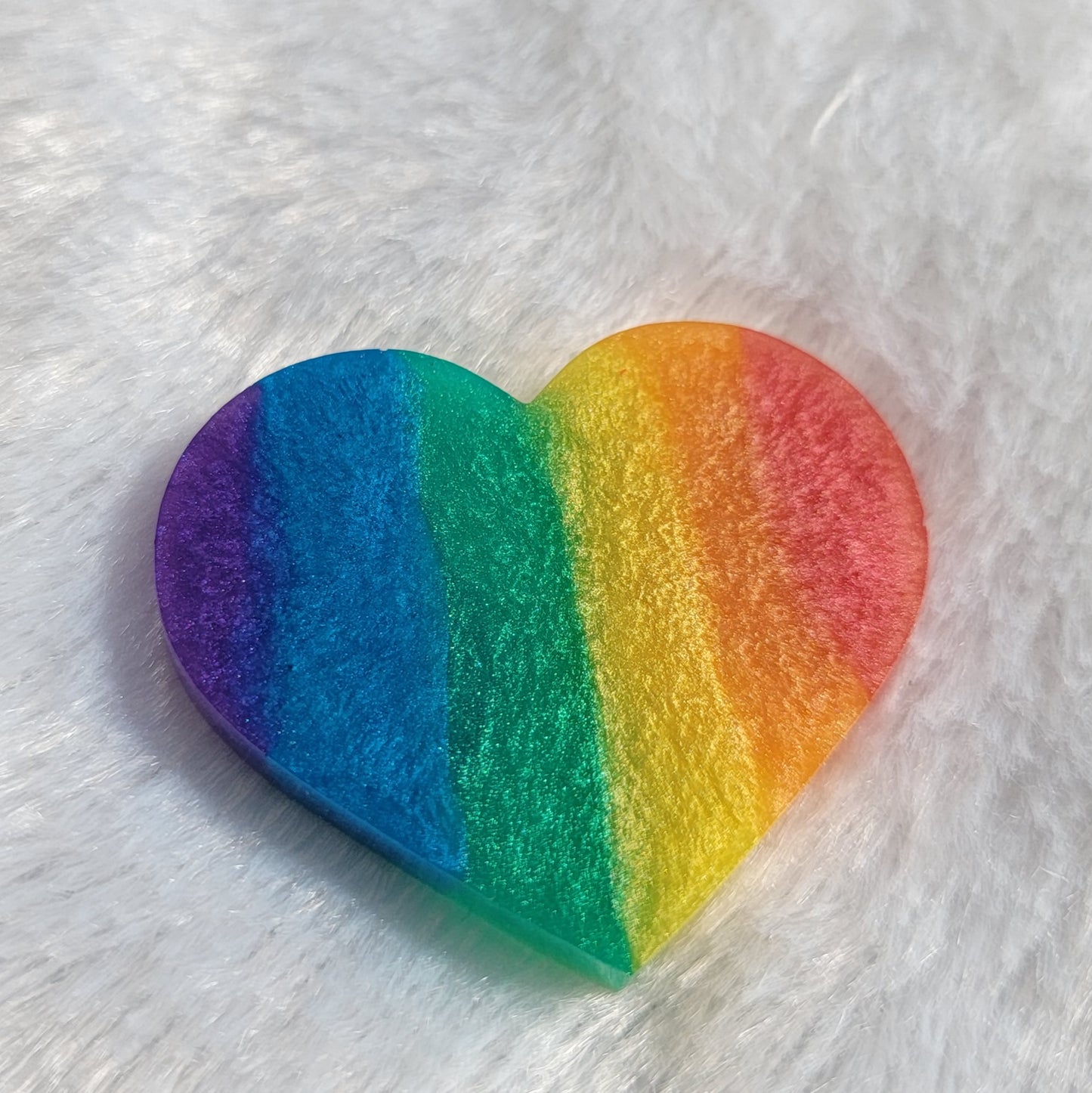 Heart shaped epoxy resin piece with vertical rainbow stripes in shimmering mica pigments.
