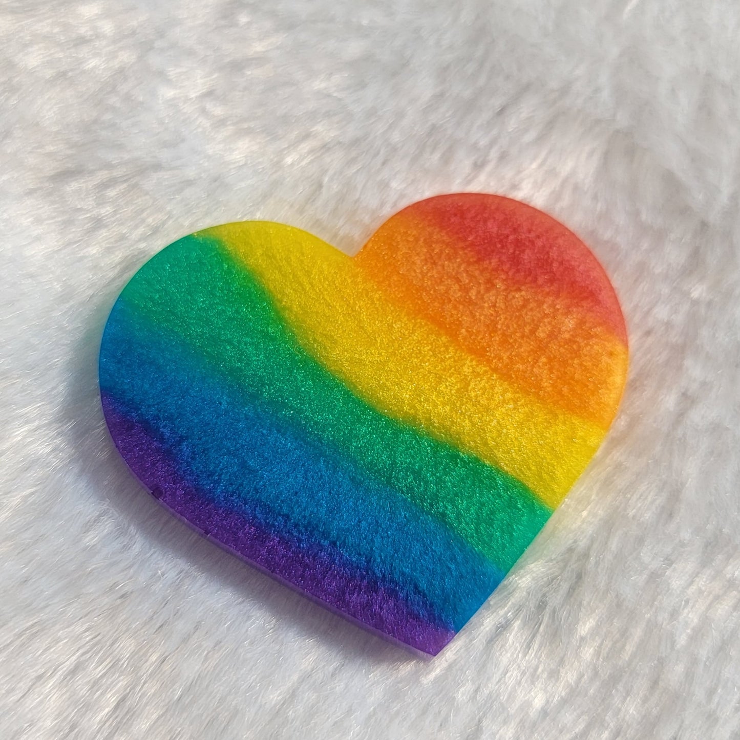 Heart shaped epoxy resin piece with diagonal rainbow stripes in shimmering mica pigments.