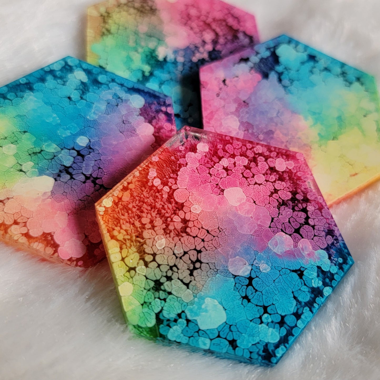 Four hexagon shaped epoxy resin pieces with rainbow ink hues.