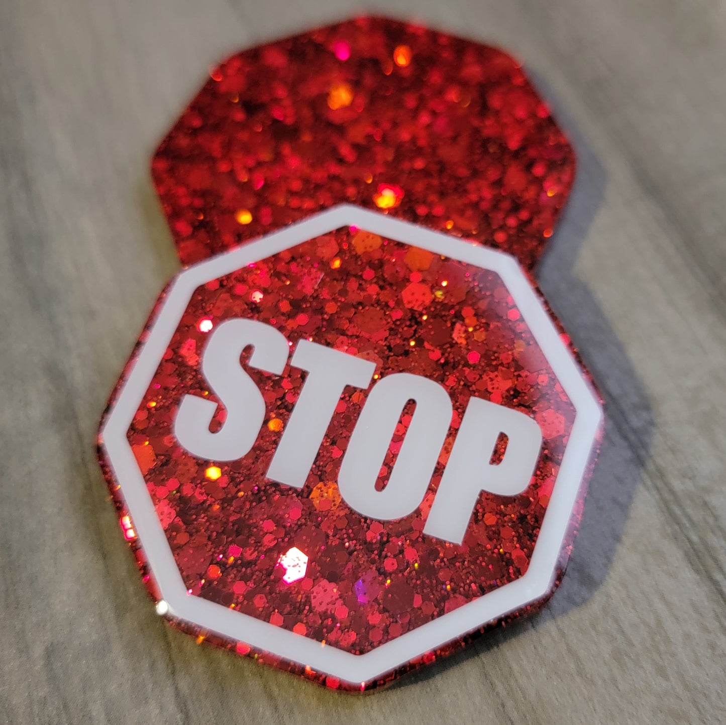 Octagon shaped epoxy resin pieces, bright red glitter, one piece has white stop sign design.