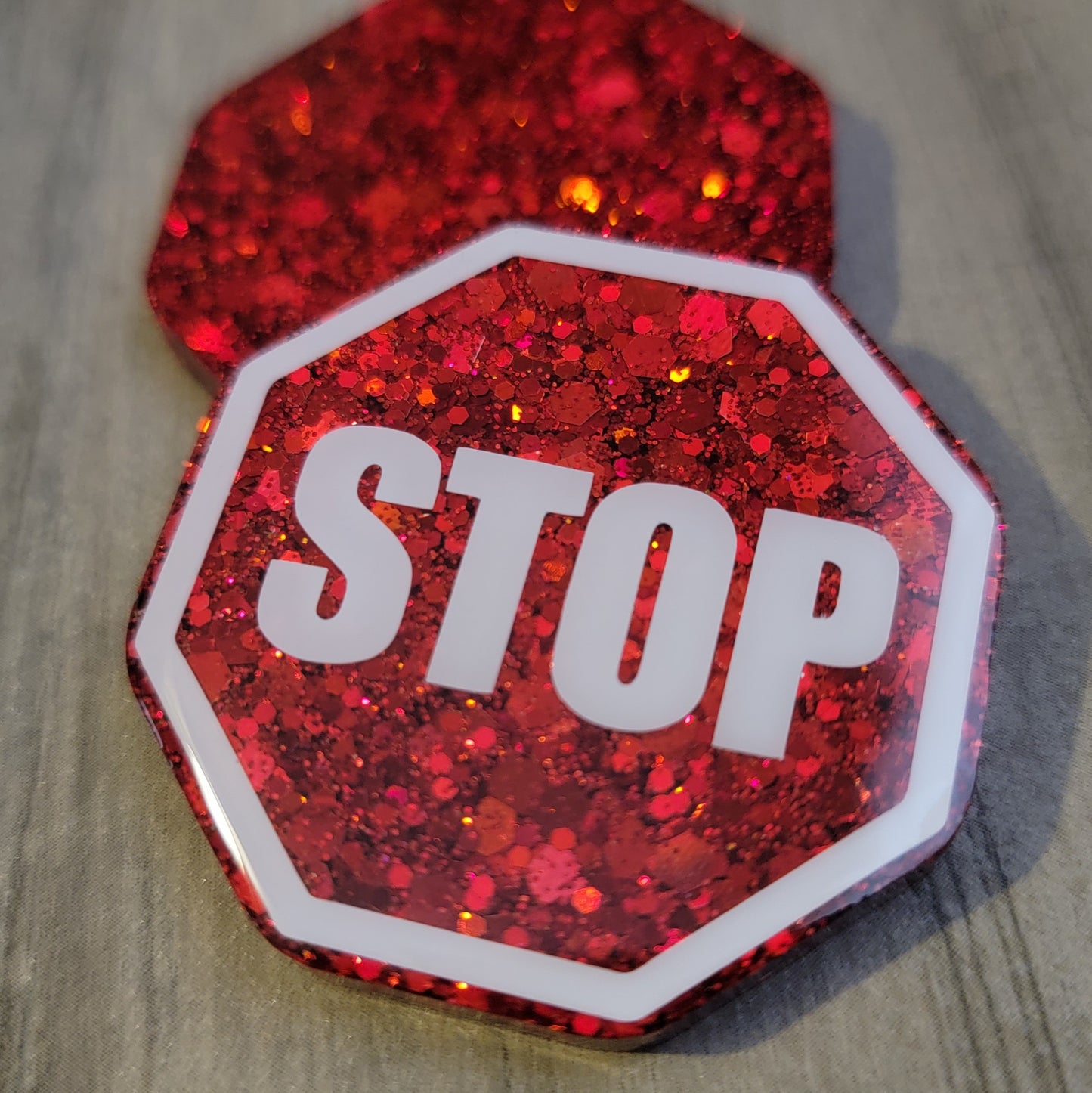 Octagon shaped epoxy resin pieces, bright red glitter, one piece has white stop sign design.