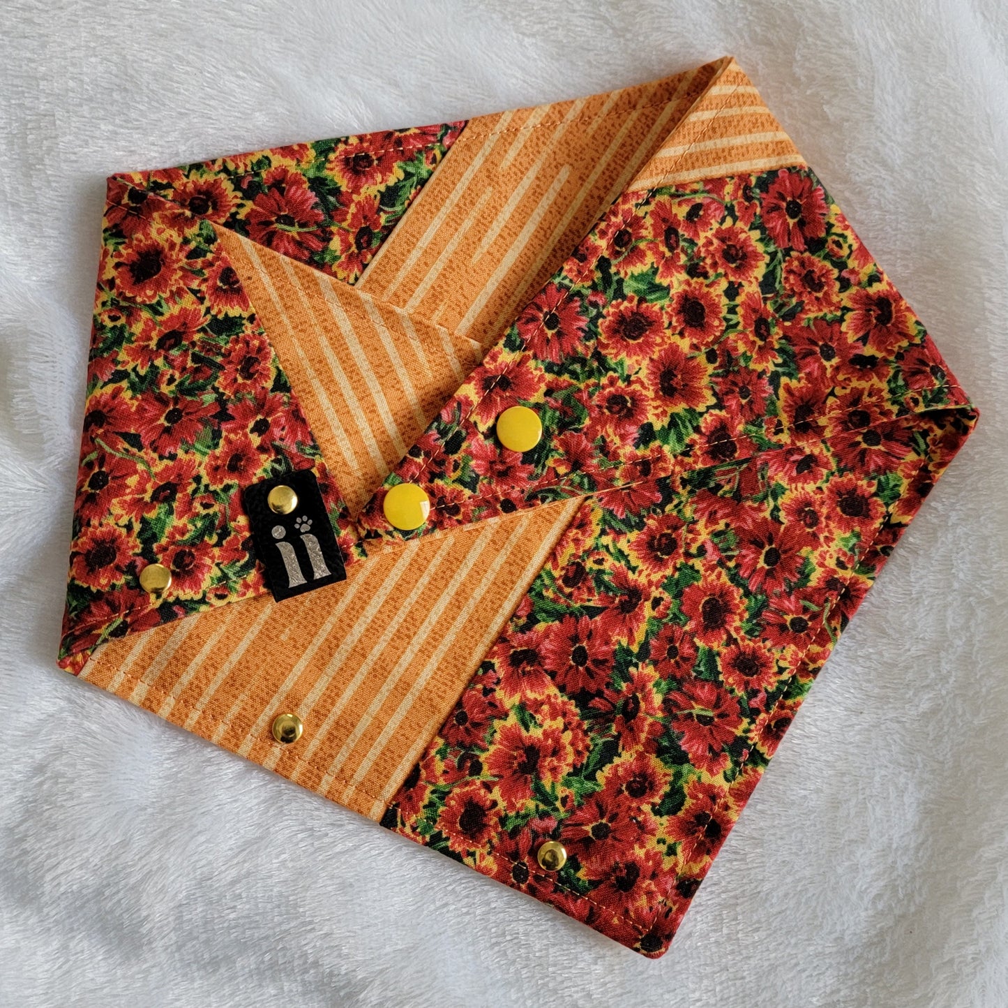 Patchwork bandana using deep rust orange floral and orange striped print. Gold tone metal rivet accents along one edge.