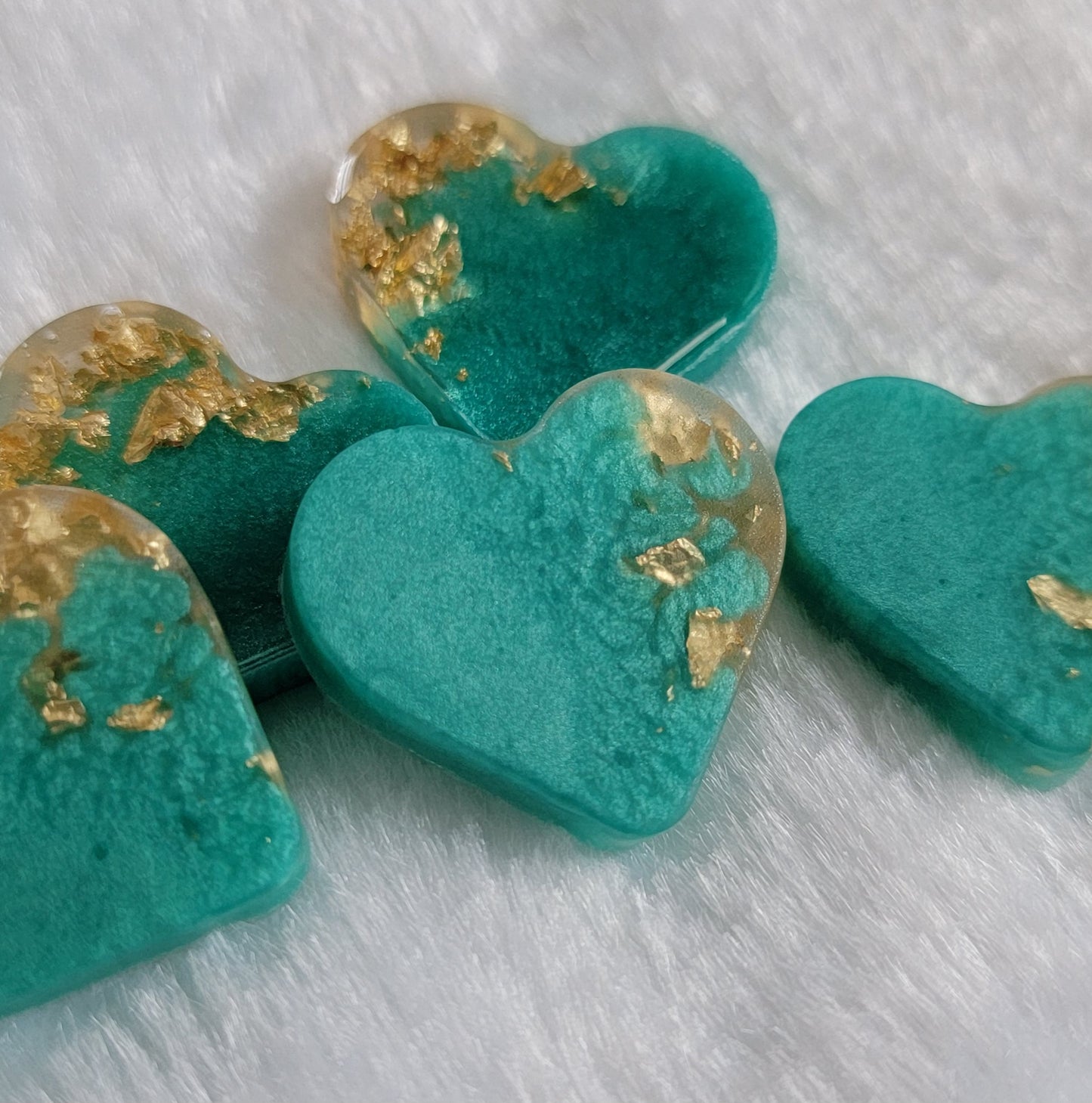 Mini heart shaped epoxy resin pieces, shimmering aqua blue pigment with gold foil flakes.