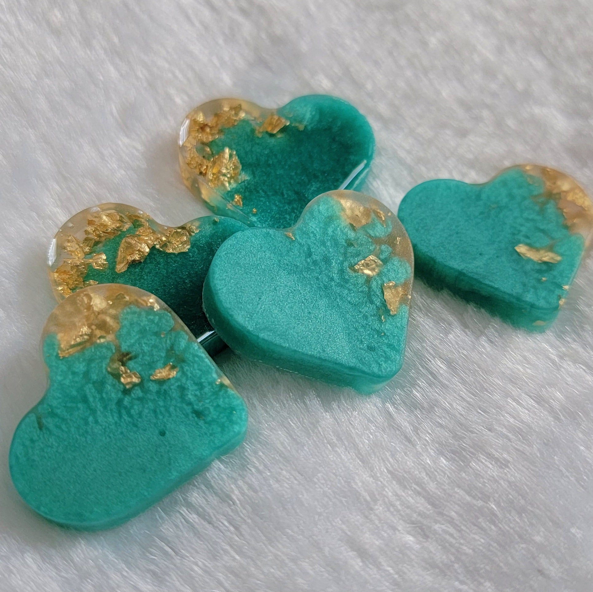 Mini heart shaped epoxy resin pieces, shimmering aqua blue pigment with gold foil flakes.