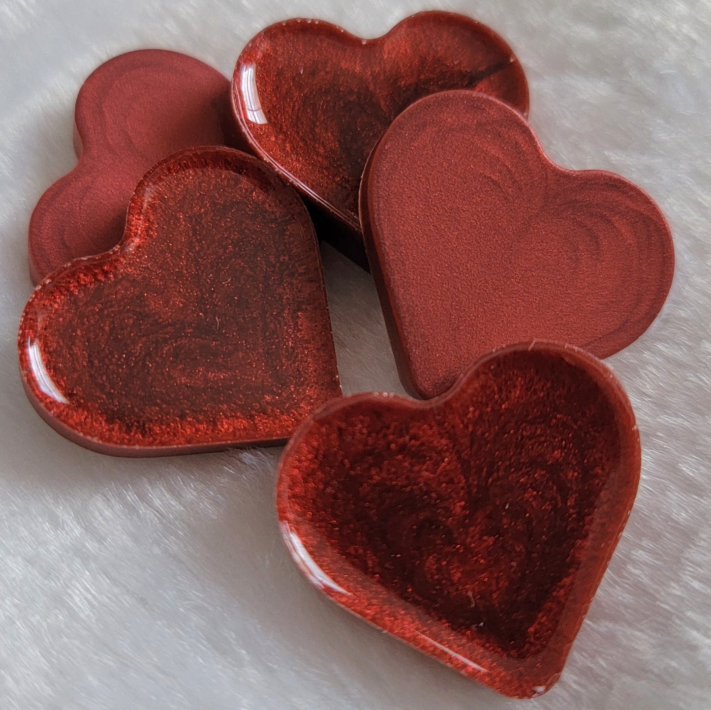 Mini heart shaped epoxy resin pieces with swirling candy red pigment.