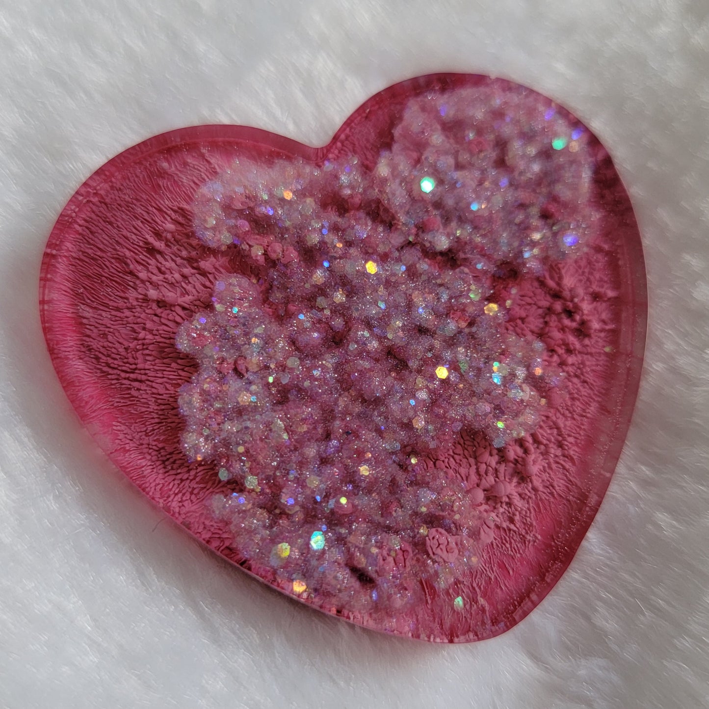 Heart shaped epoxy resin piece with dark pink ink pigment and glitter swirls.